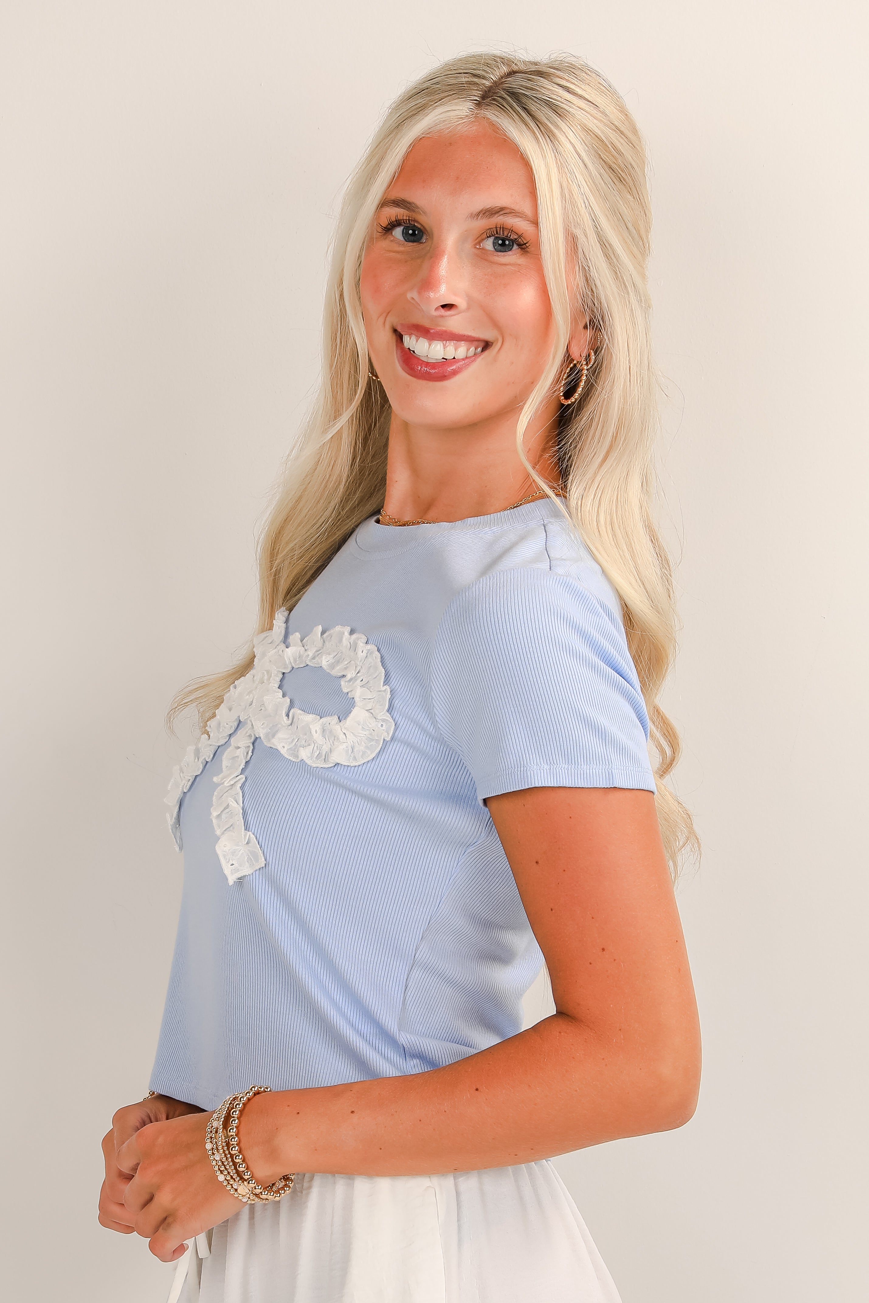 Woman wearing a light blue dress with lace details on a plain background