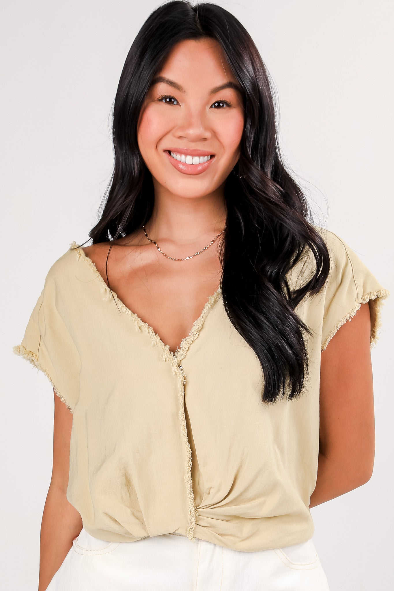 Woman wearing a light-colored blouse with a plain background