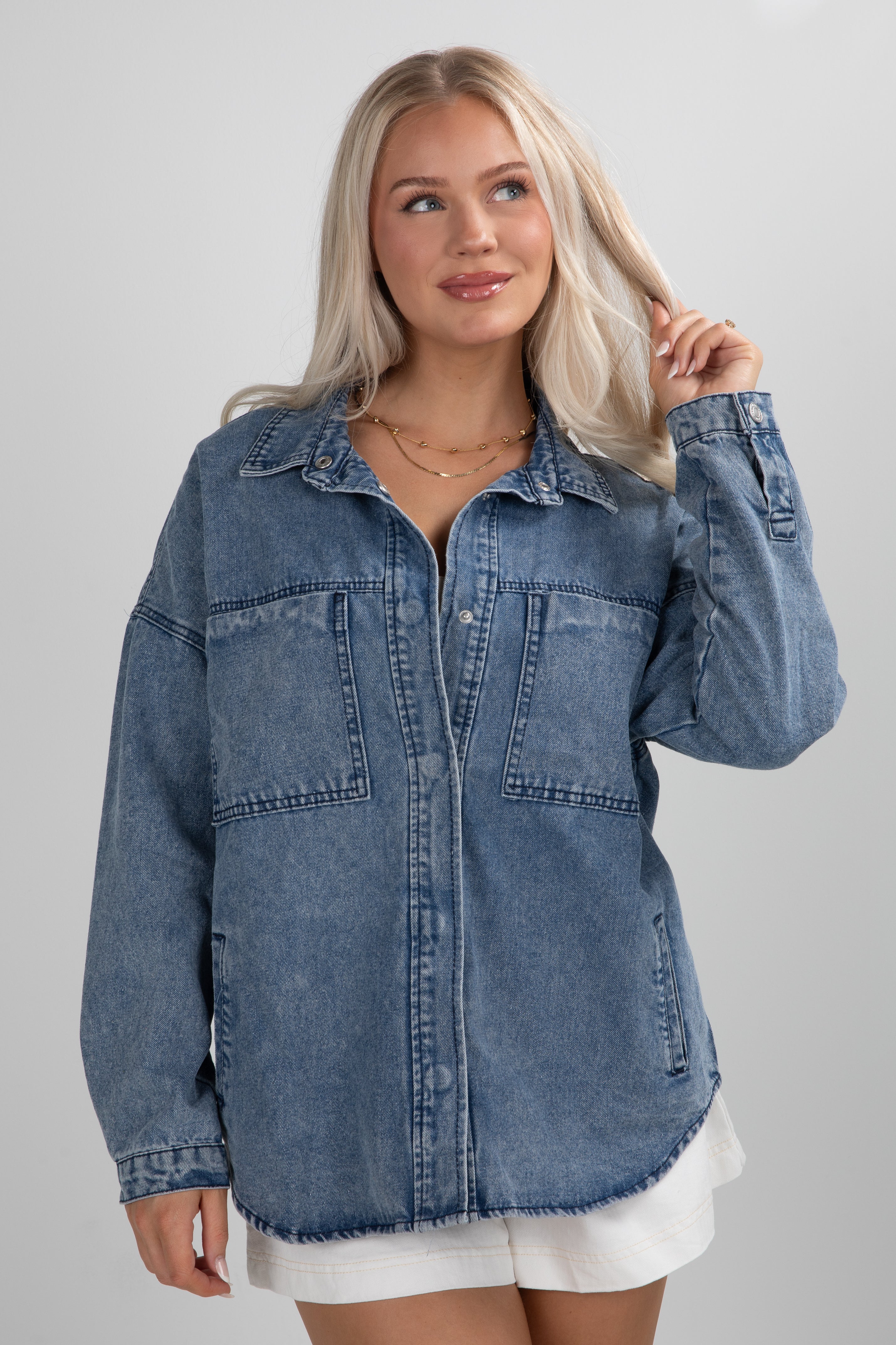 Woman wearing a blue denim jacket on a gray background