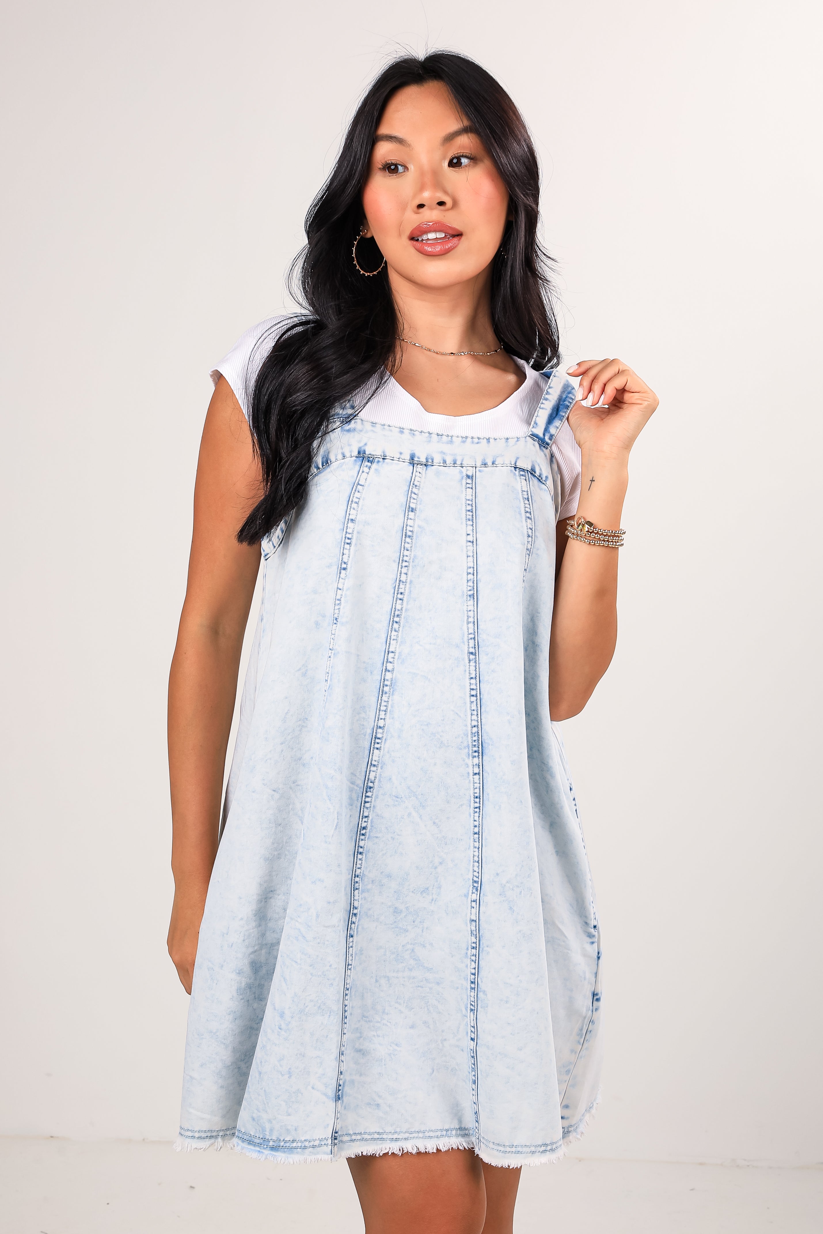 Woman wearing a light blue denim dress against a plain background
