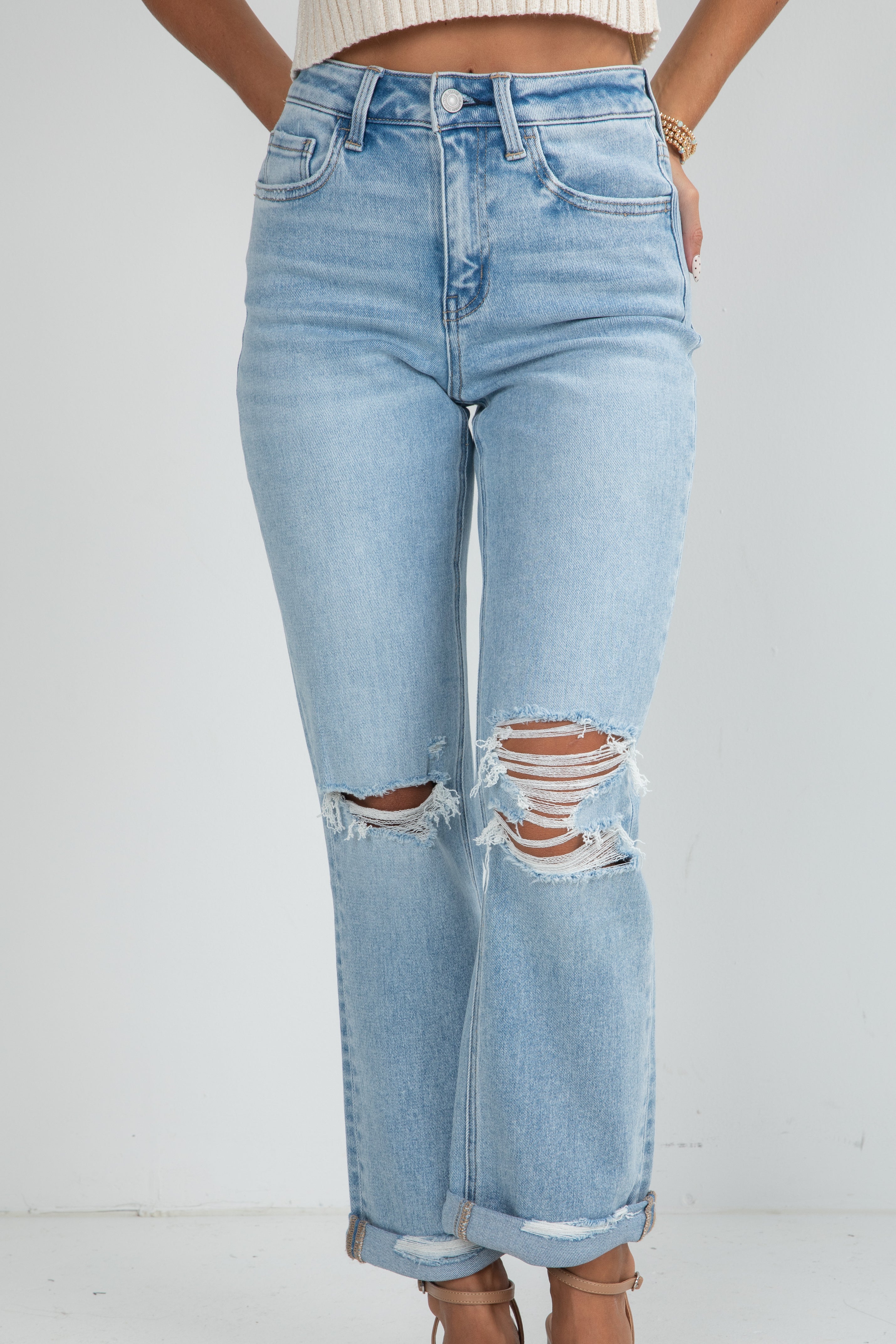 Light blue jeans with distressing details on a white background