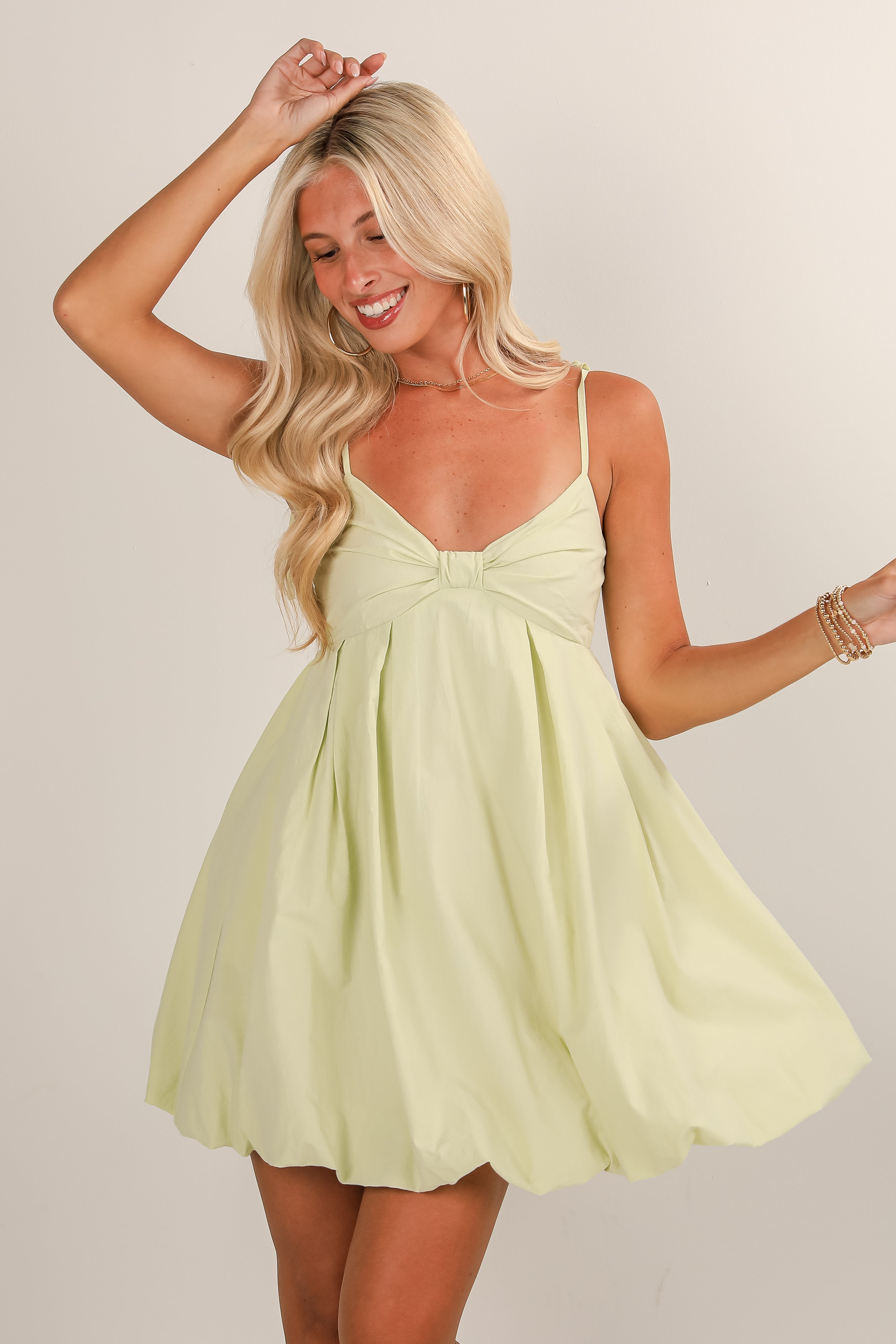 Woman wearing a light yellow dress against a plain background
