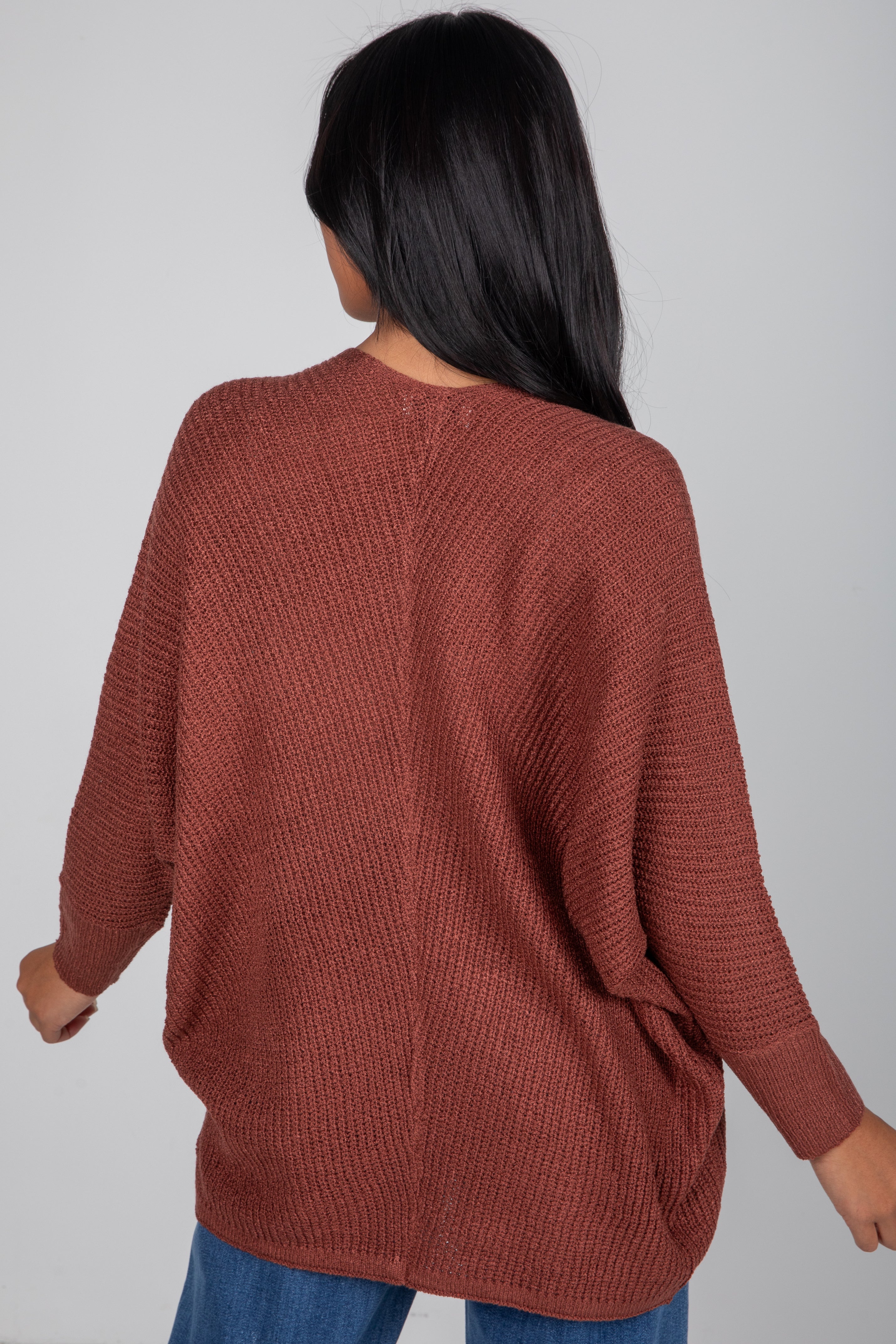 Person wearing a brown textured sweater on a plain background