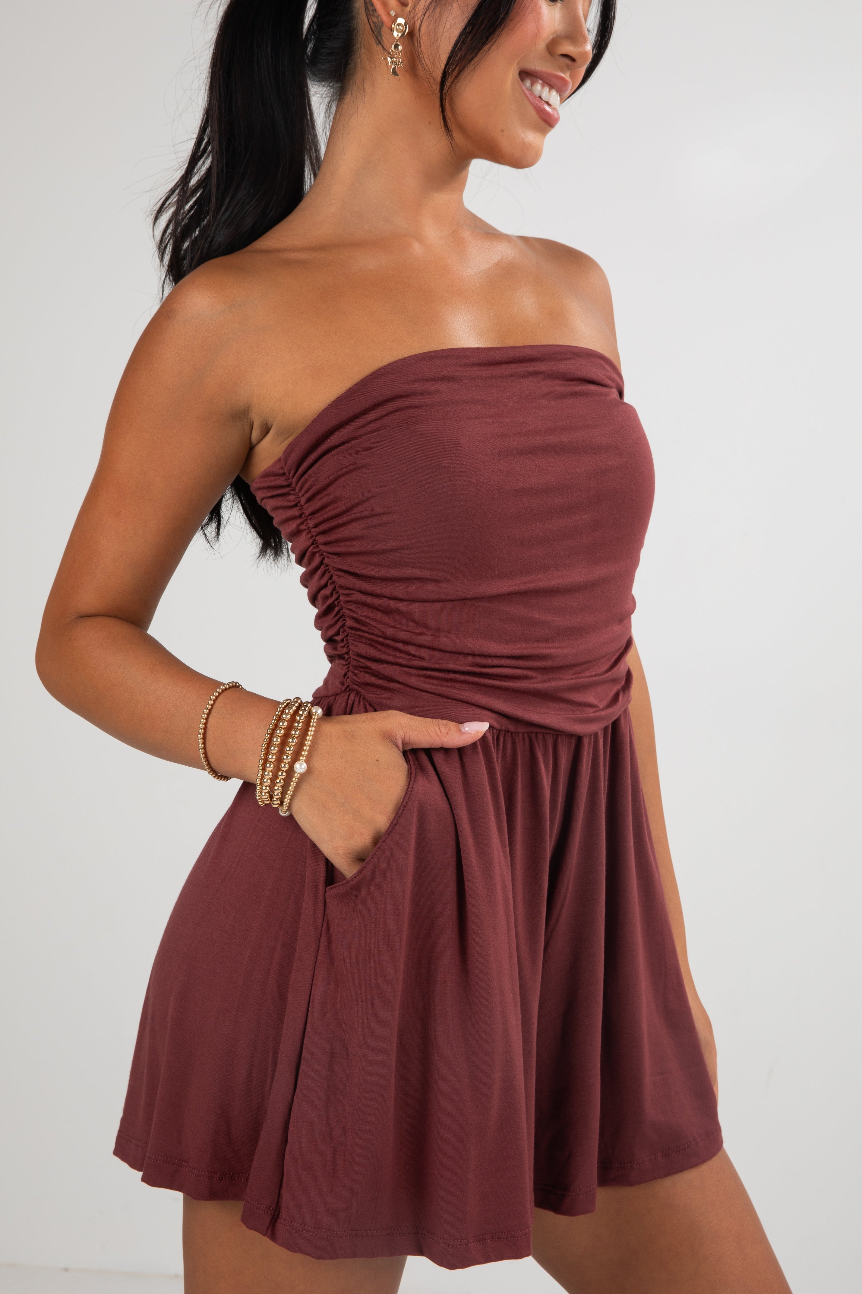 Woman wearing a strapless burgundy dress on a white background