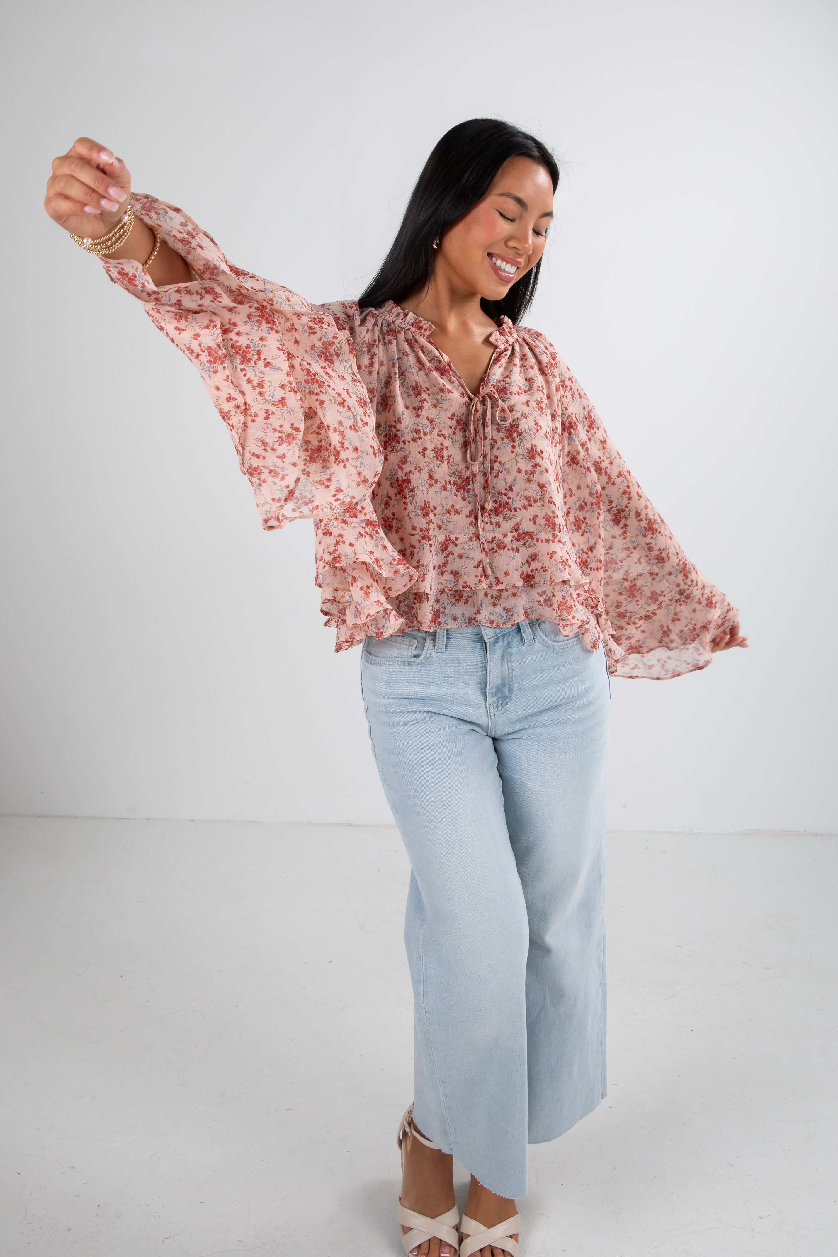 Woman wearing a floral blouse and light blue jeans on a white background
