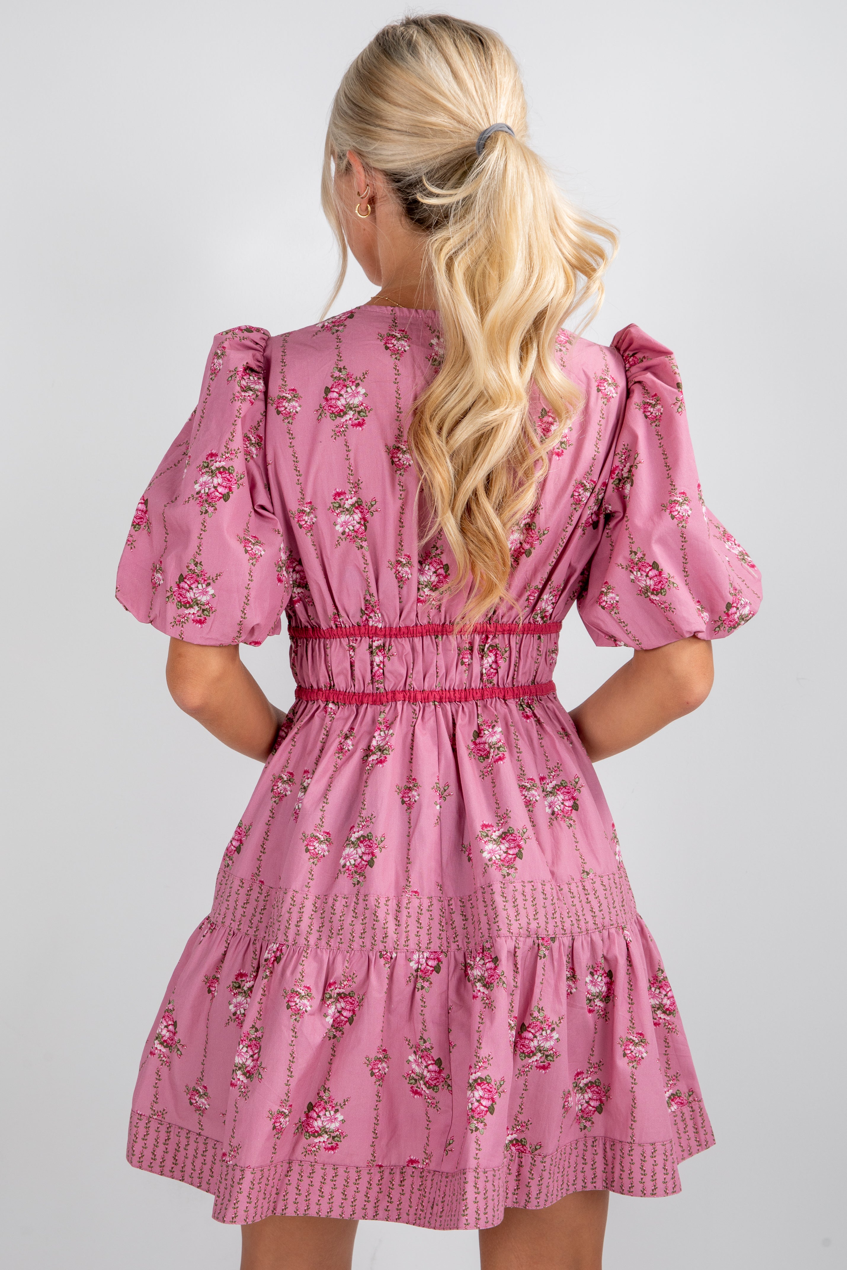 Pink floral dress with puff sleeves worn by a person on a plain background