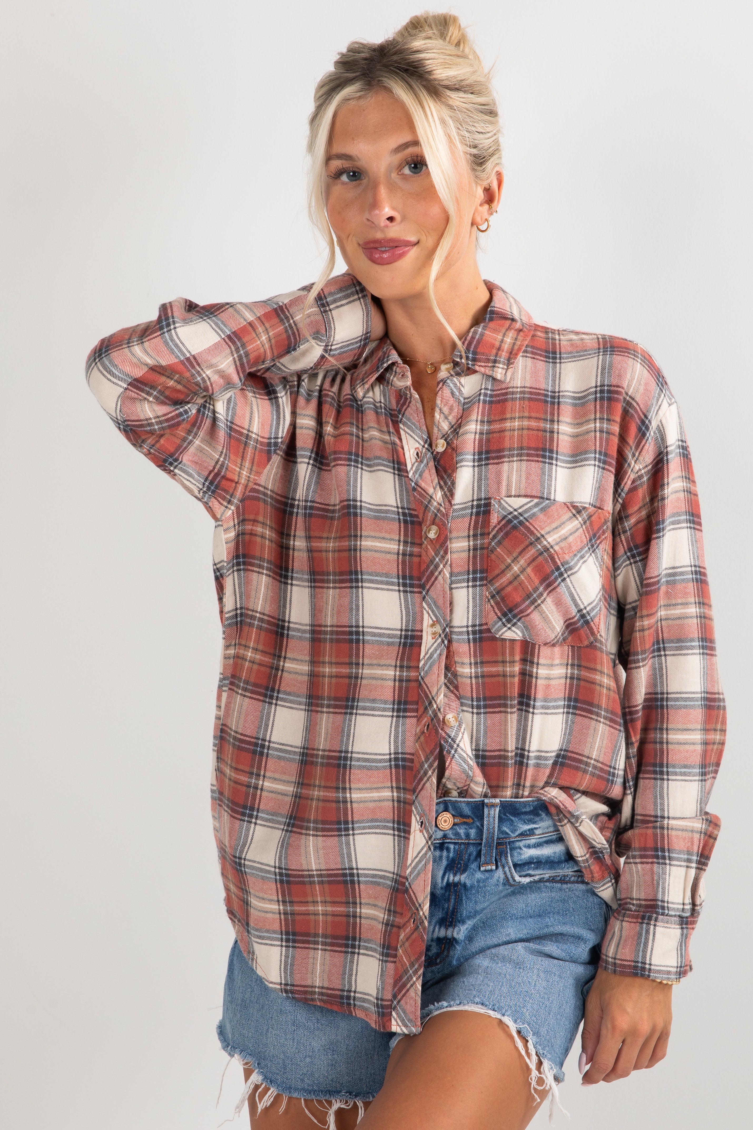 Woman wearing a plaid shirt and denim shorts on a plain background
