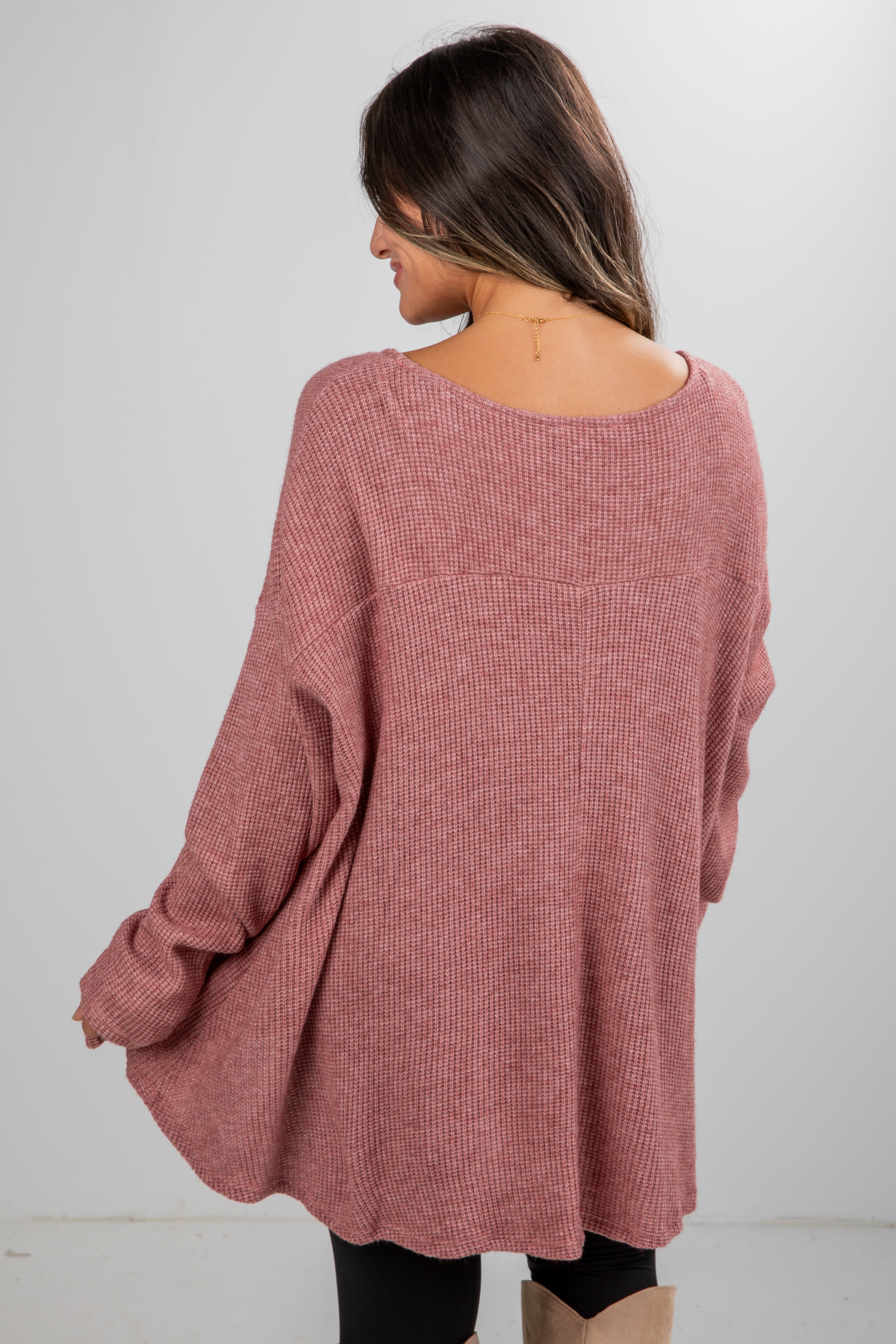Person wearing a pink sweater against a white background
