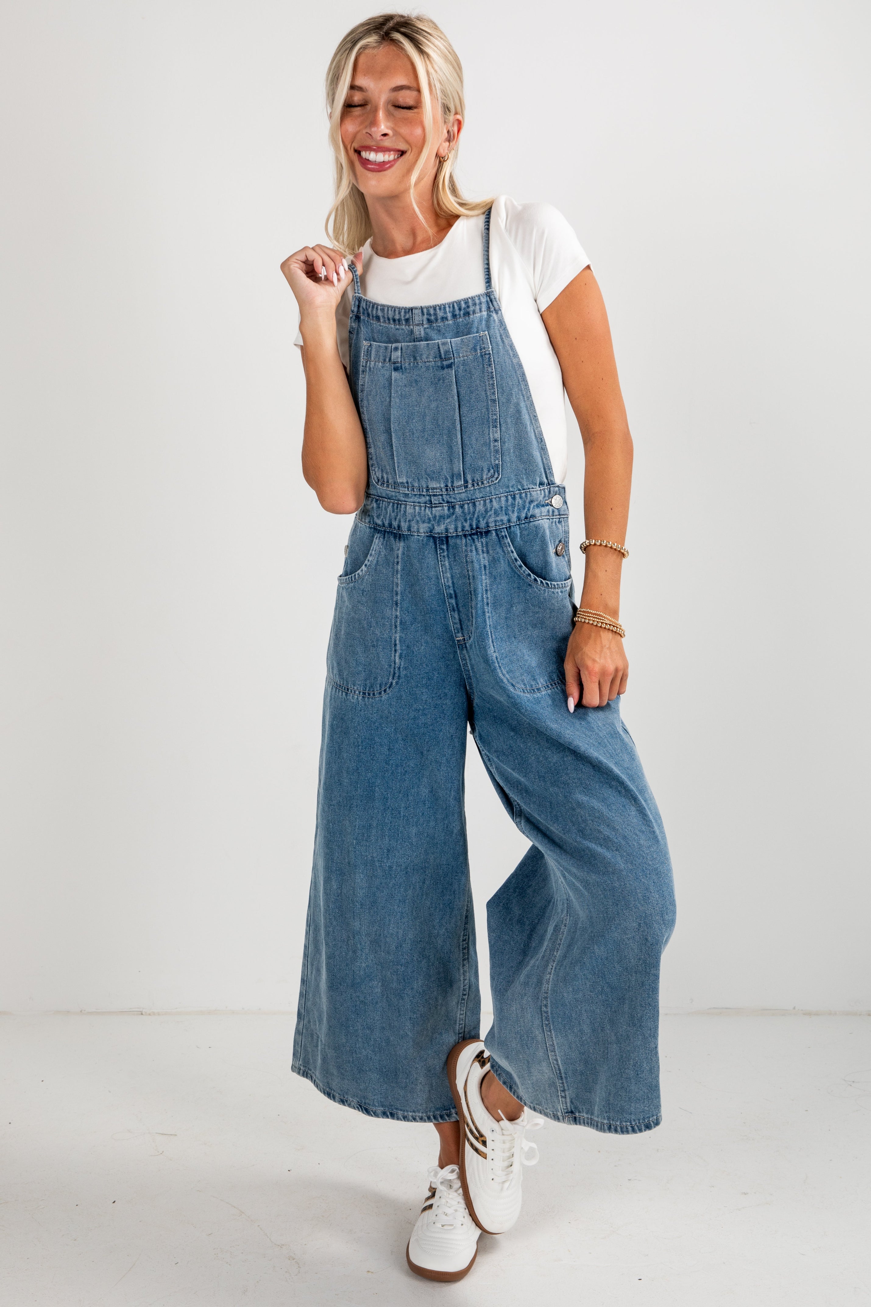 Woman wearing blue denim overalls on a white background