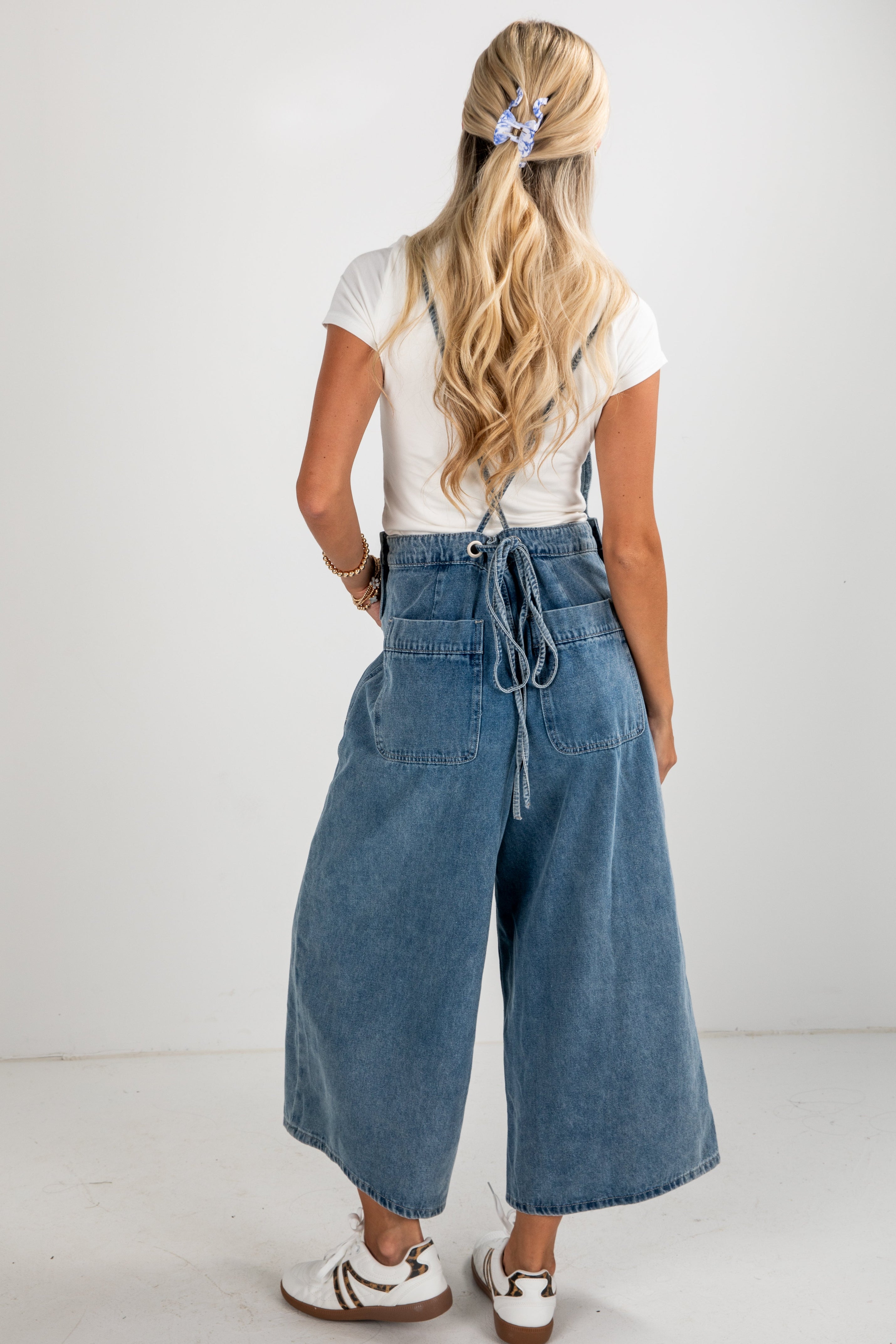 Person wearing a white t-shirt and blue denim wide-leg pants on a plain background