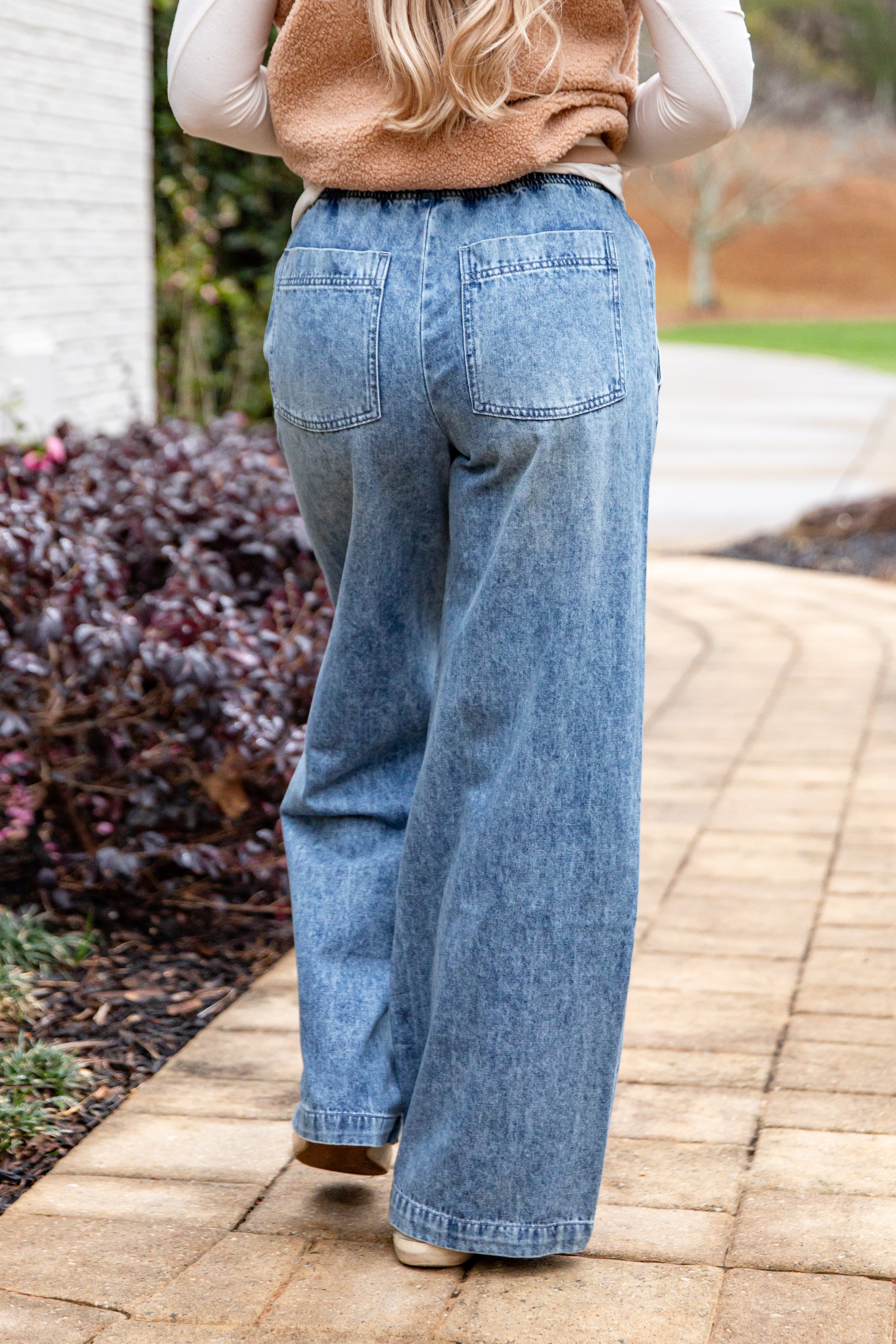 Person wearing blue jeans walking on a paved path with a blurred background