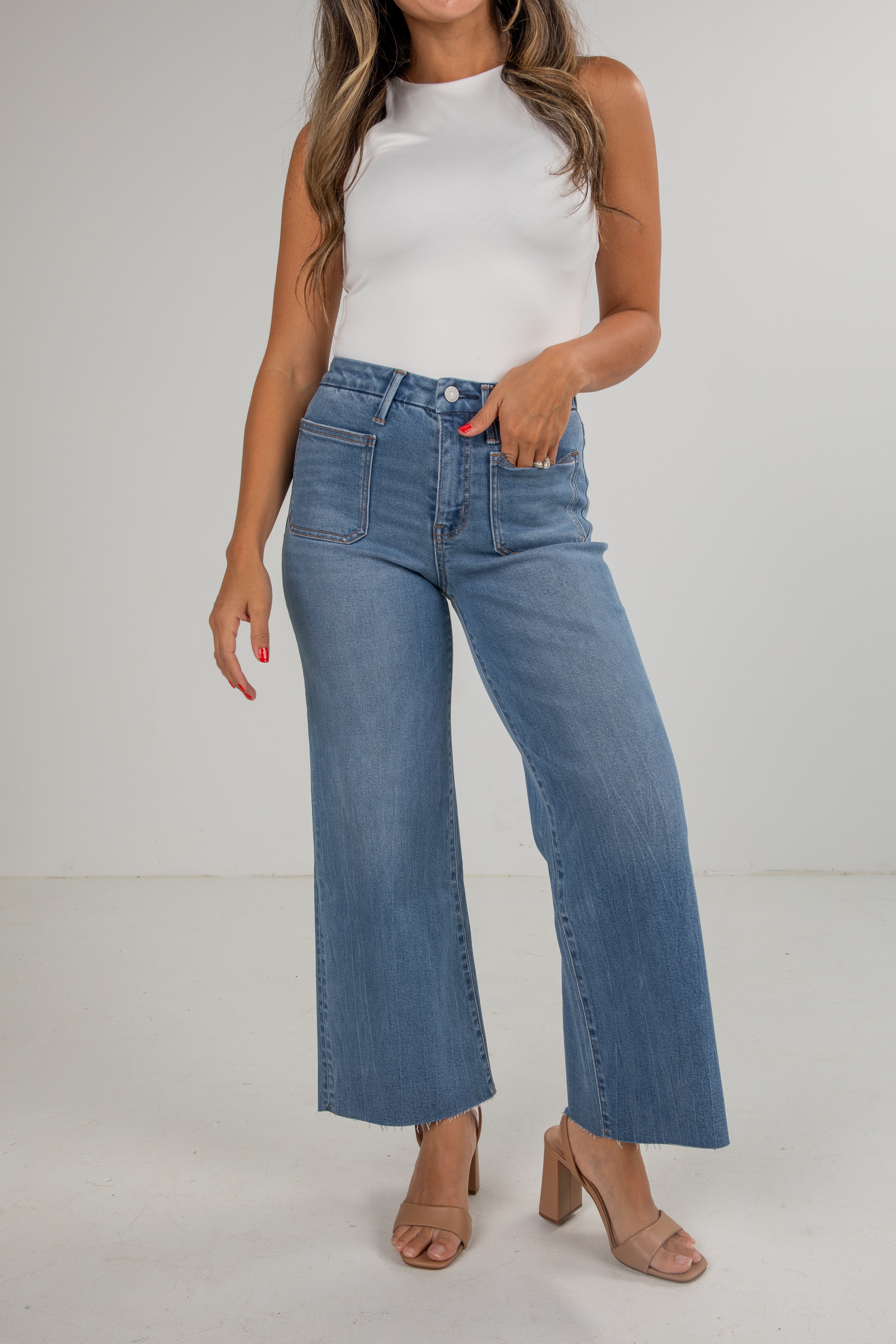 Woman wearing a white top and blue jeans on a plain background