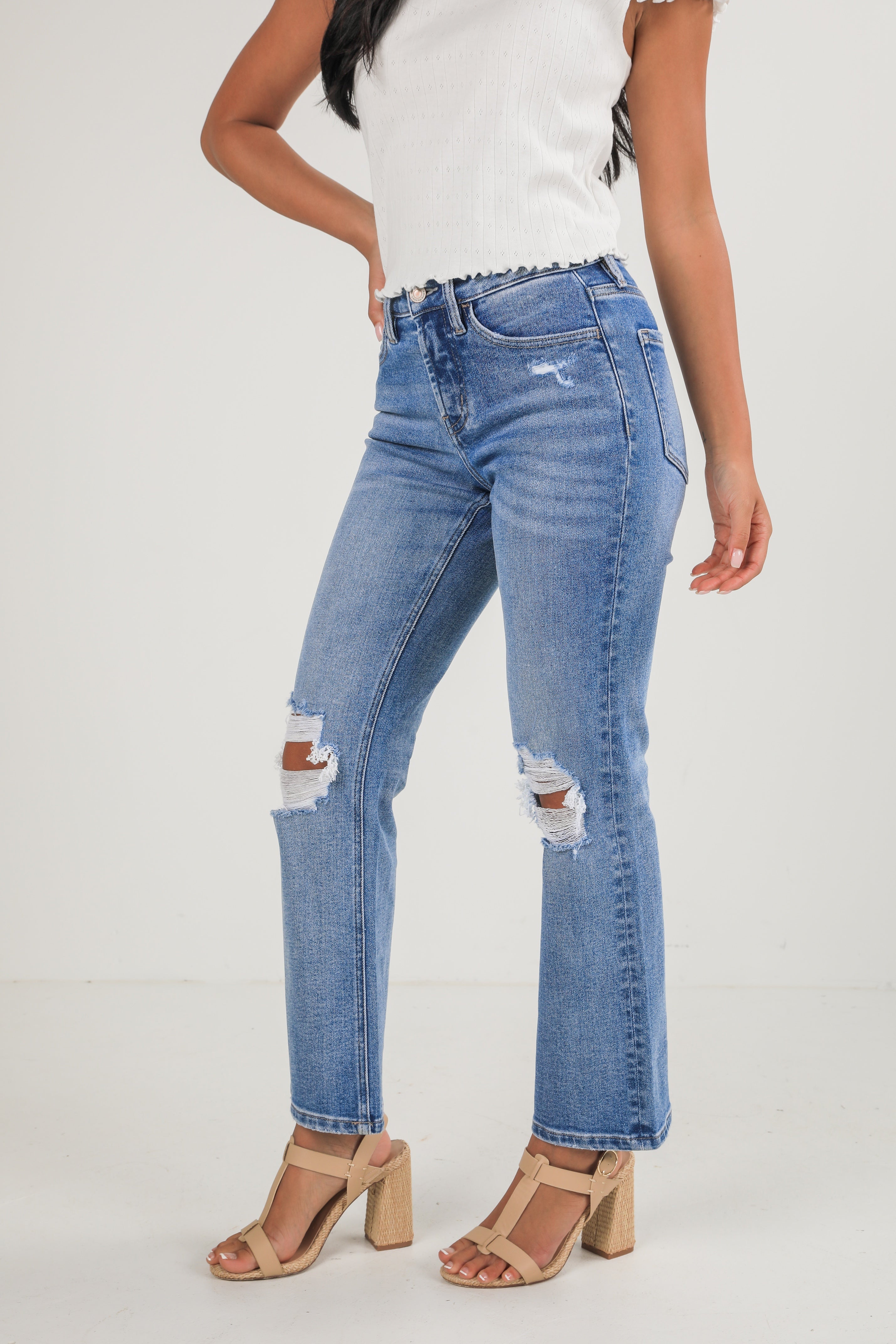 Person wearing distressed blue jeans on a white background