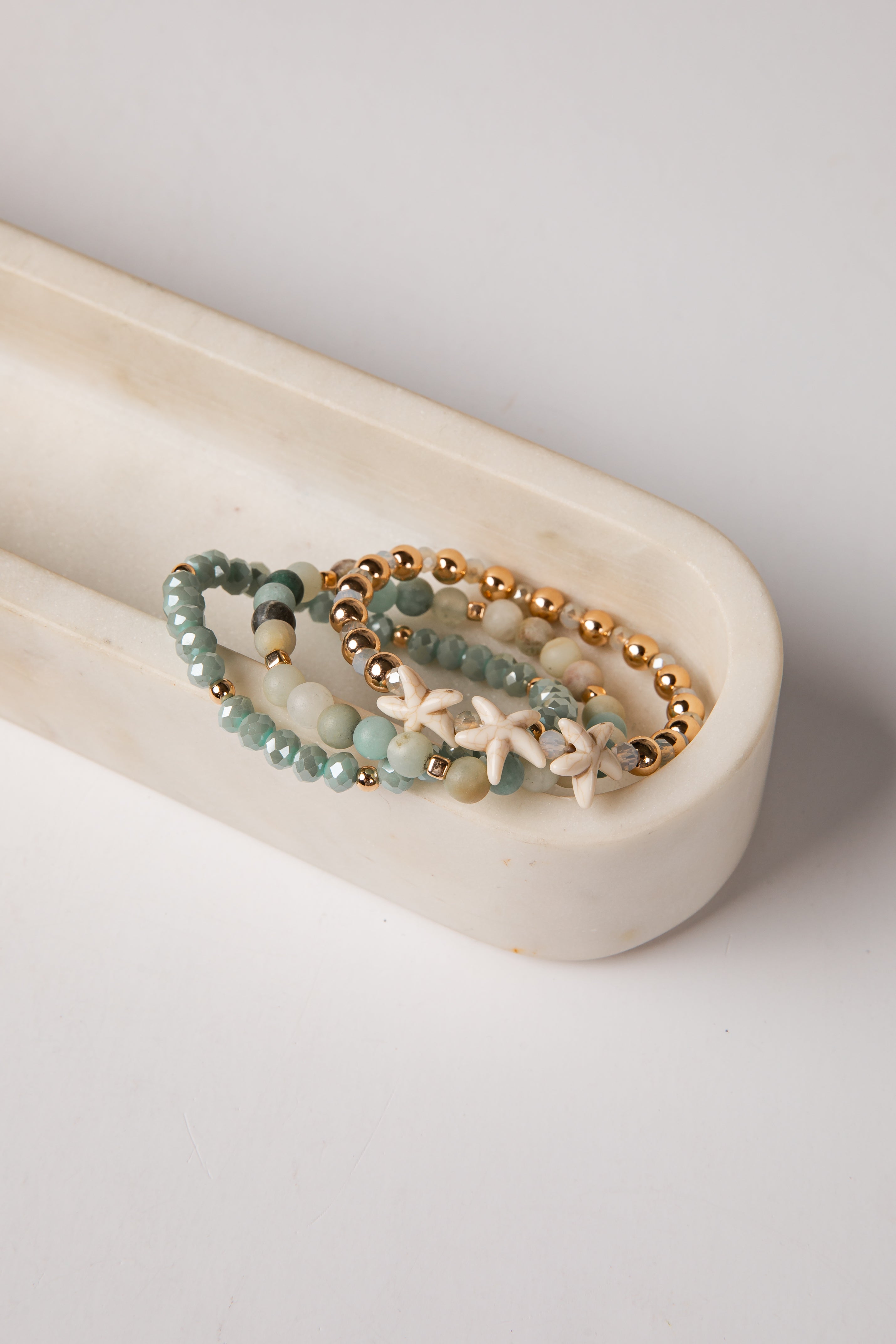 Set of beaded bracelets with starfish charm on a white dish