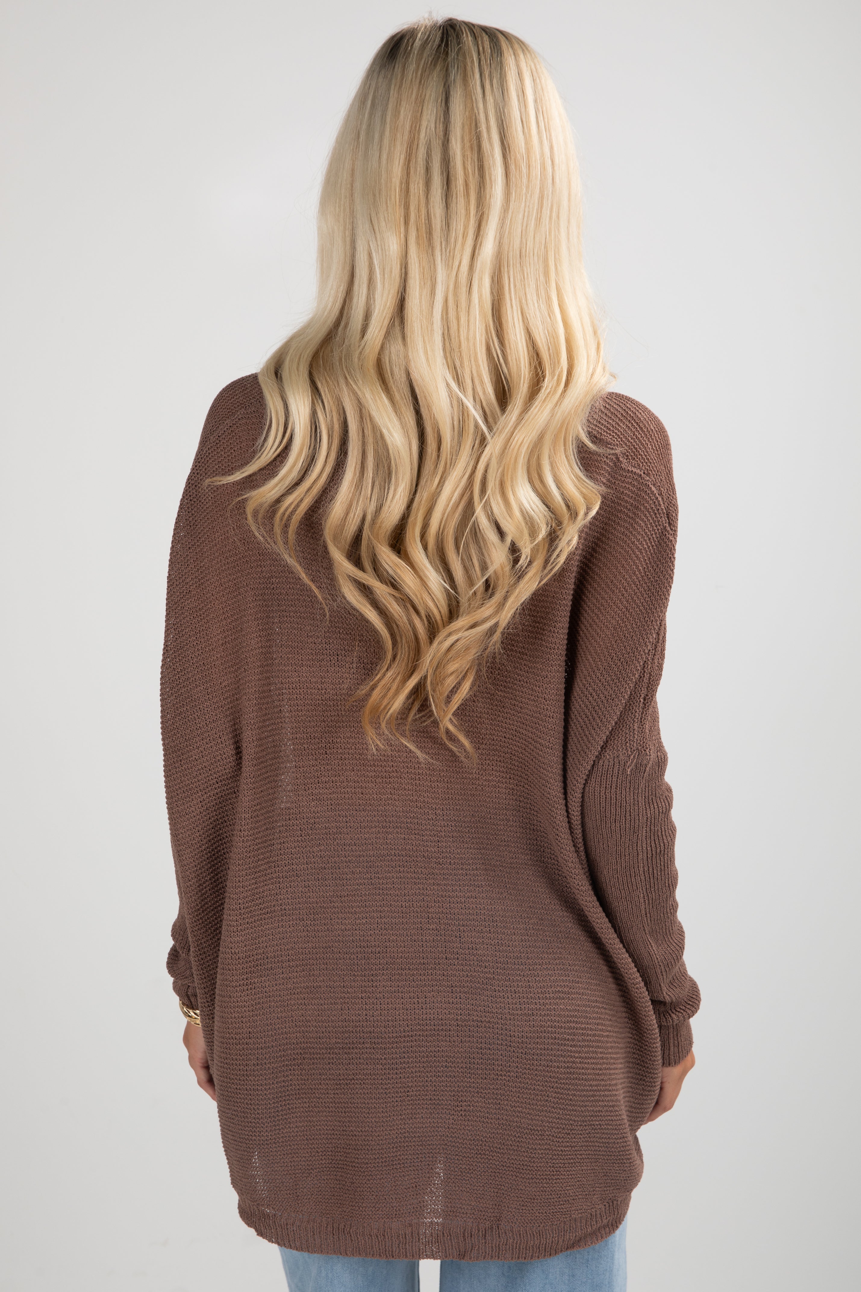 Person wearing a brown sweater from behind on a plain background