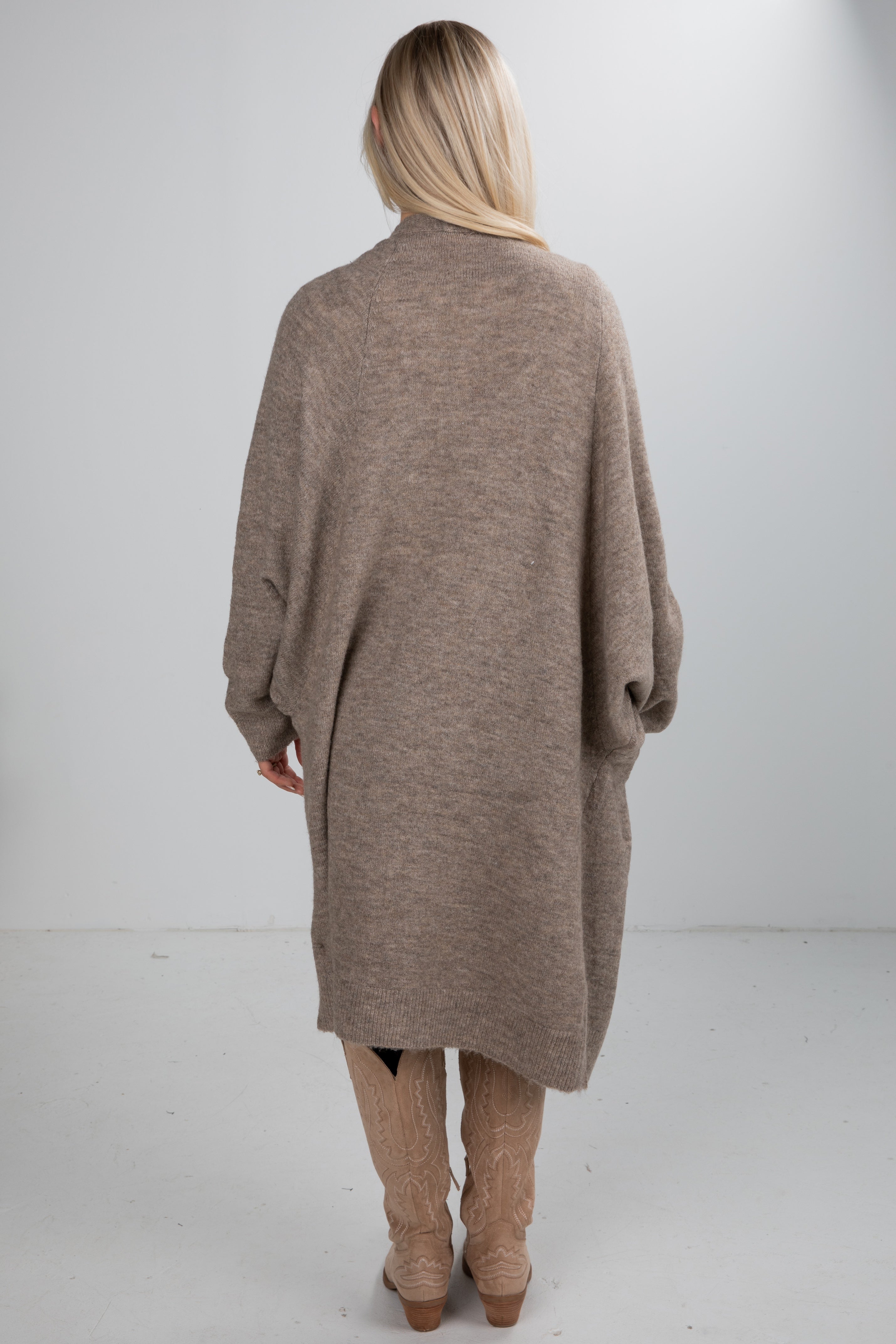 Person wearing a long brown cardigan on a white background