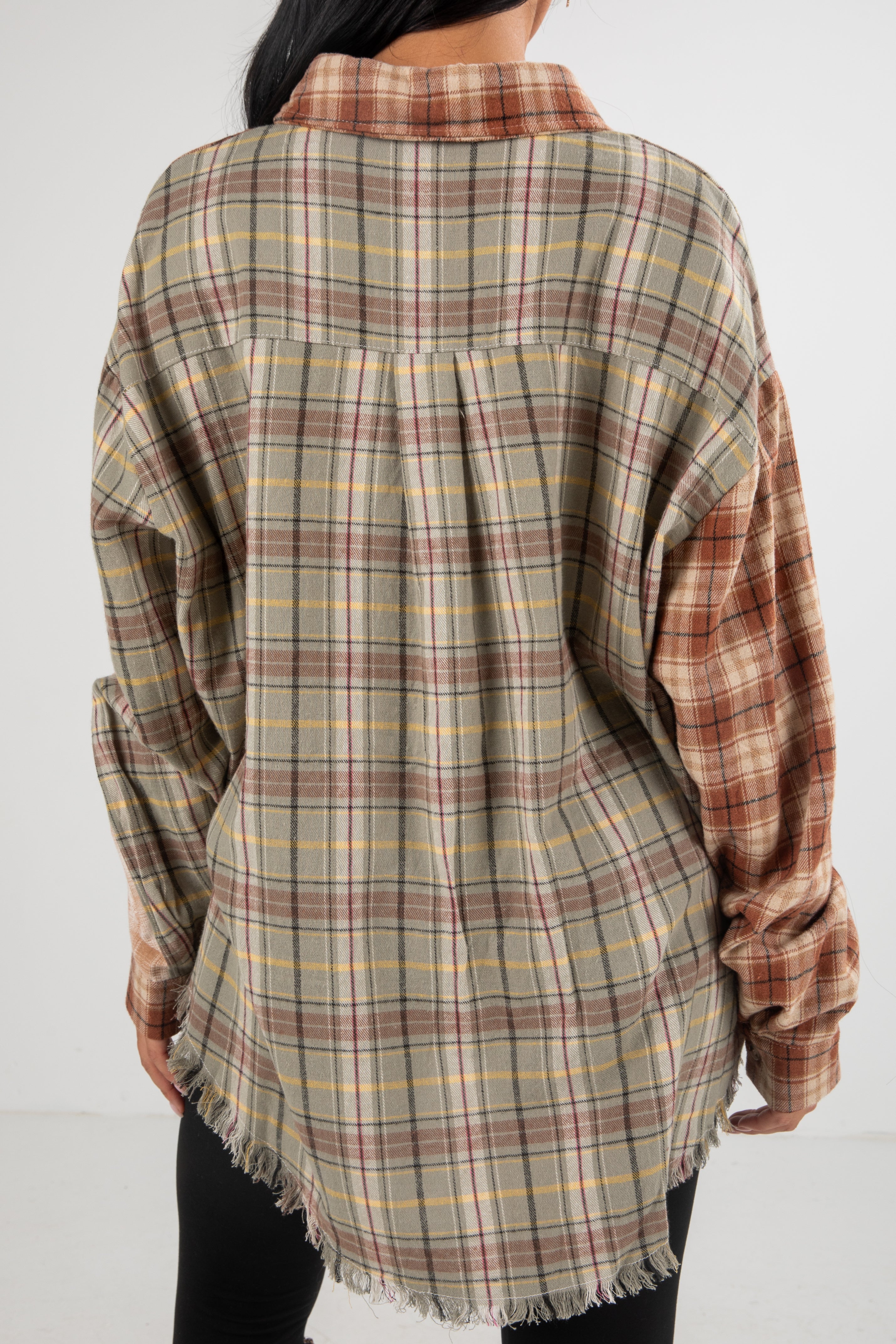 Plaid shirt with frayed edges worn by a person on a white background