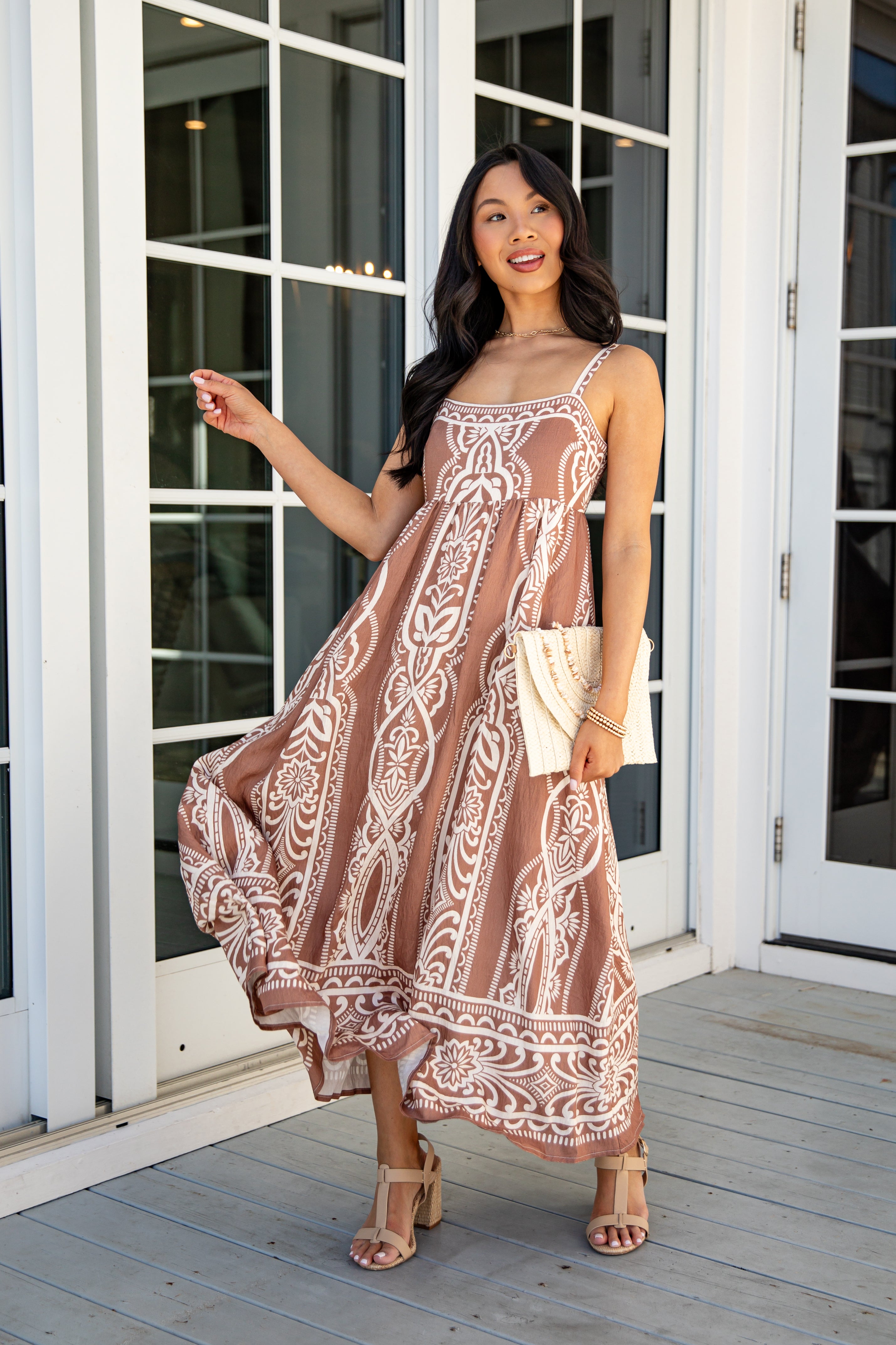 Woman in a patterned dress standing on a wooden deck.
