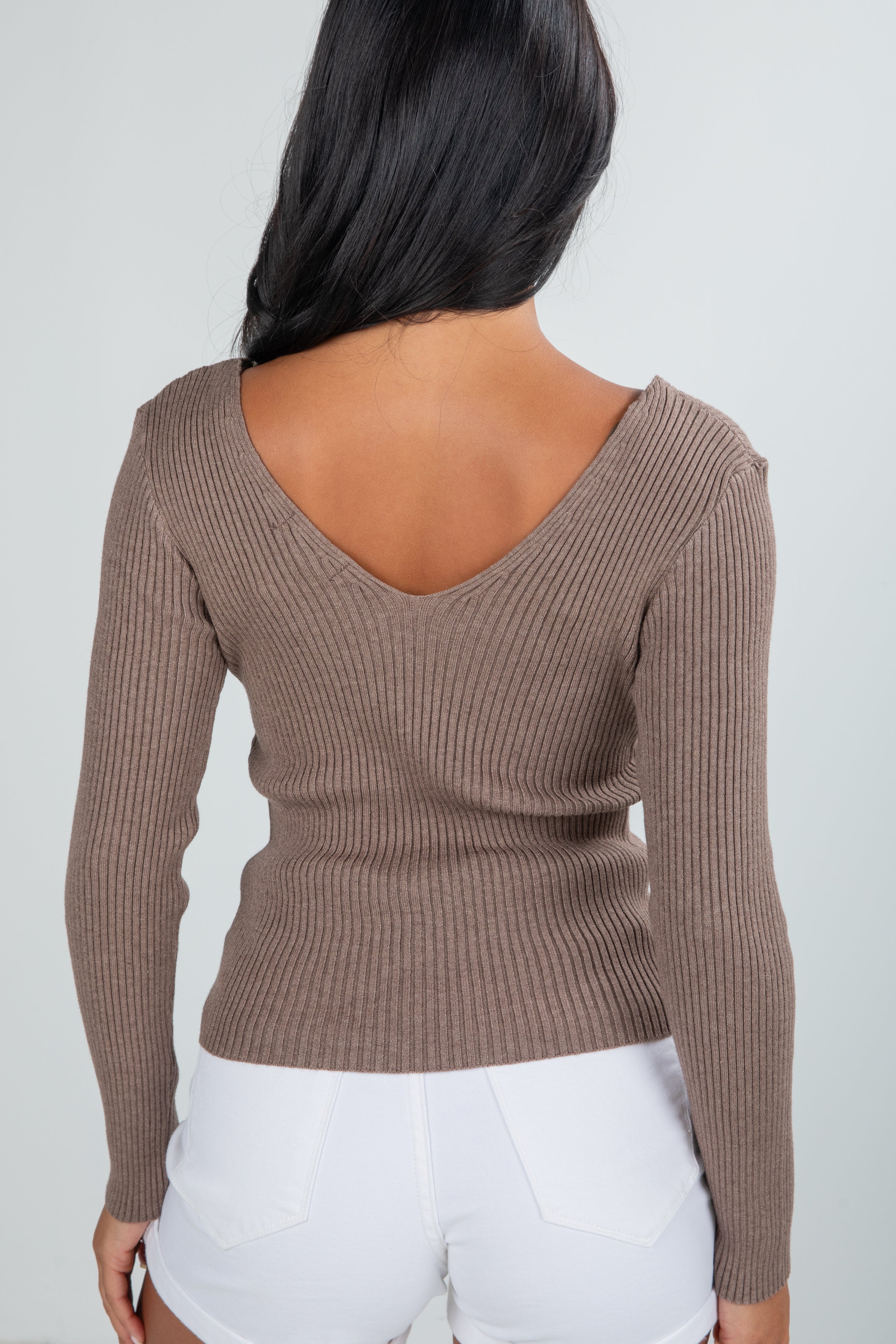 Brown ribbed sweater worn by a person on a plain background