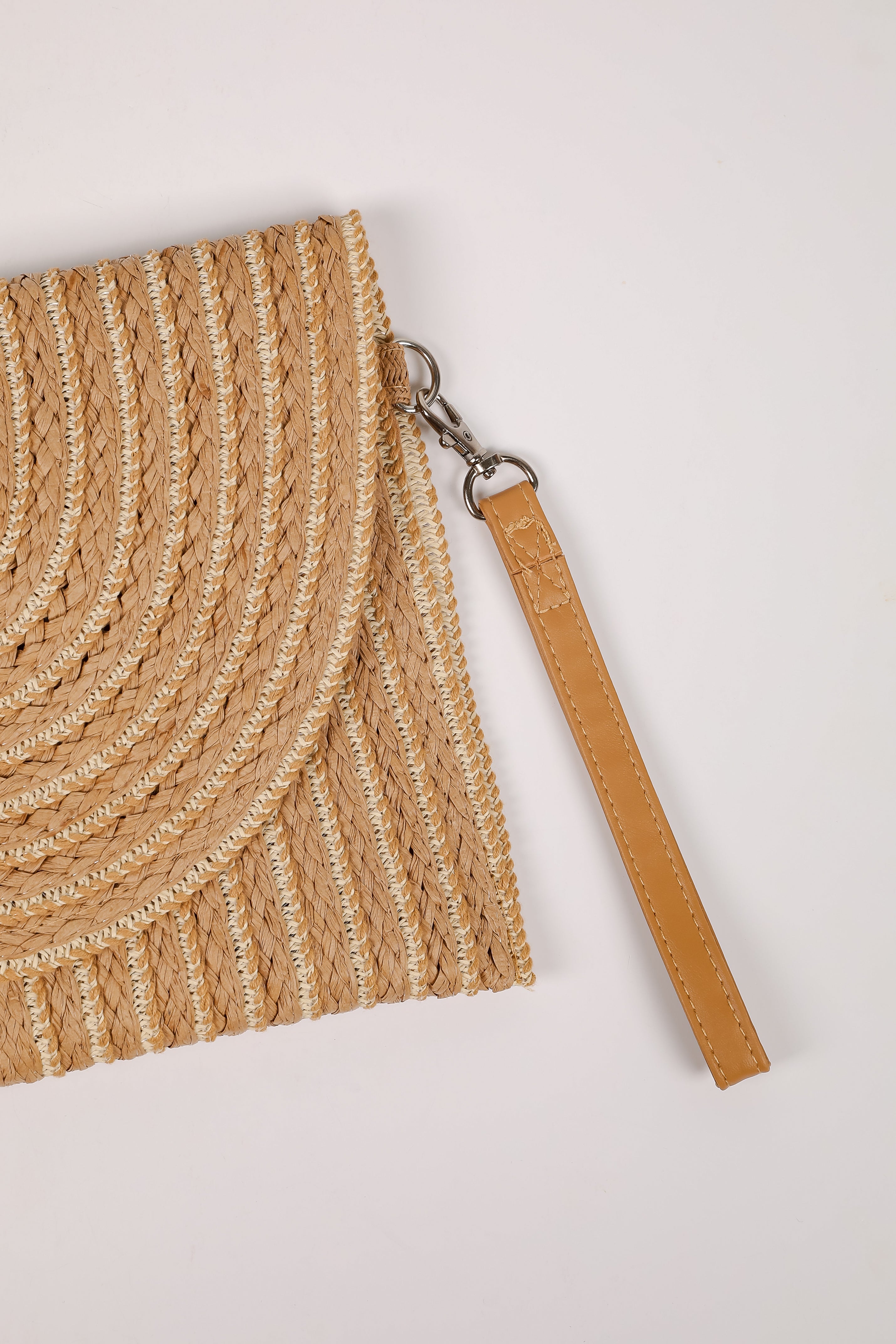 Close-up of a woven beige bag with a leather strap on a light gray background