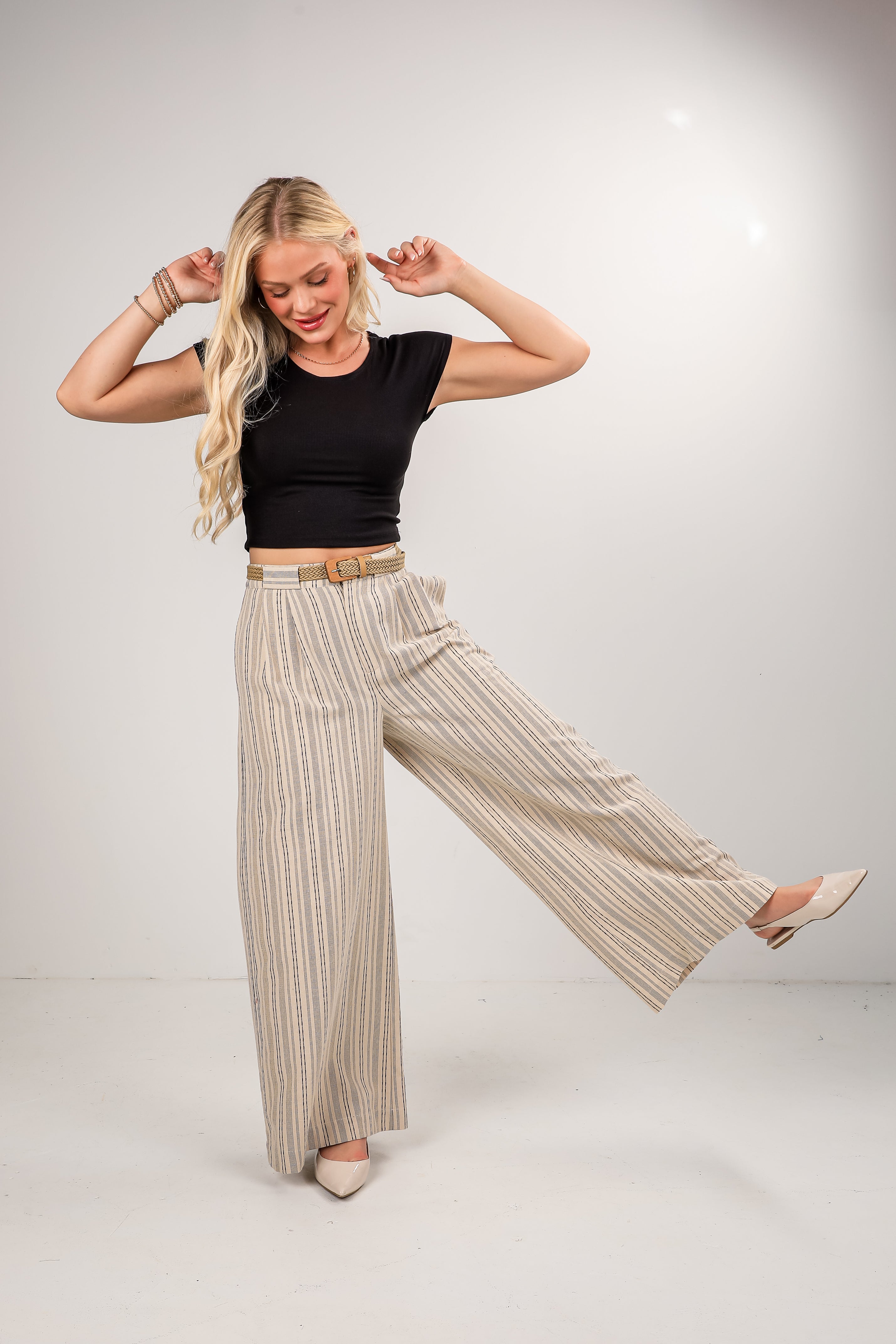 Woman wearing a black top and beige striped pants on a white background