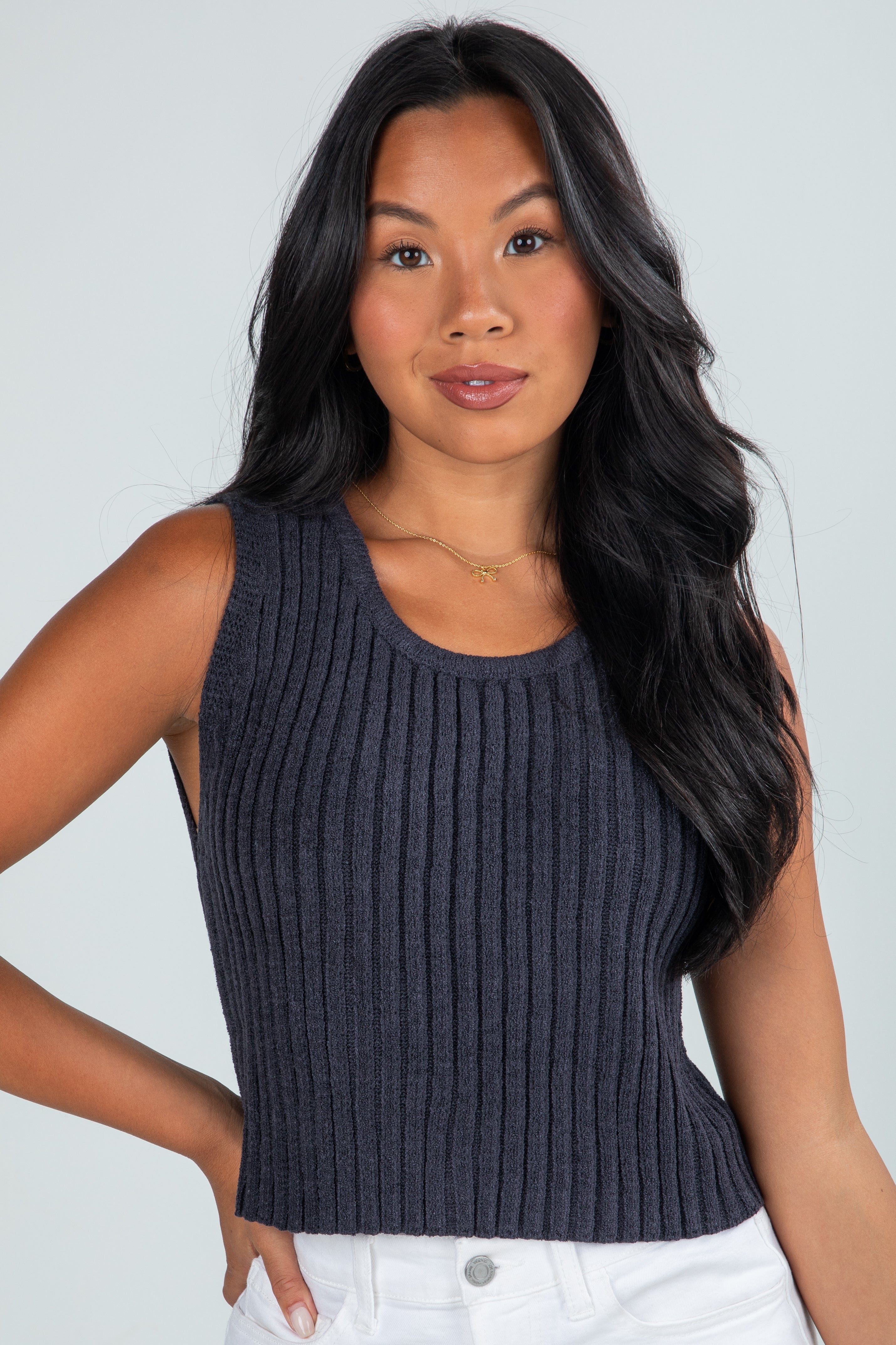Woman wearing a dark ribbed tank top against a plain background