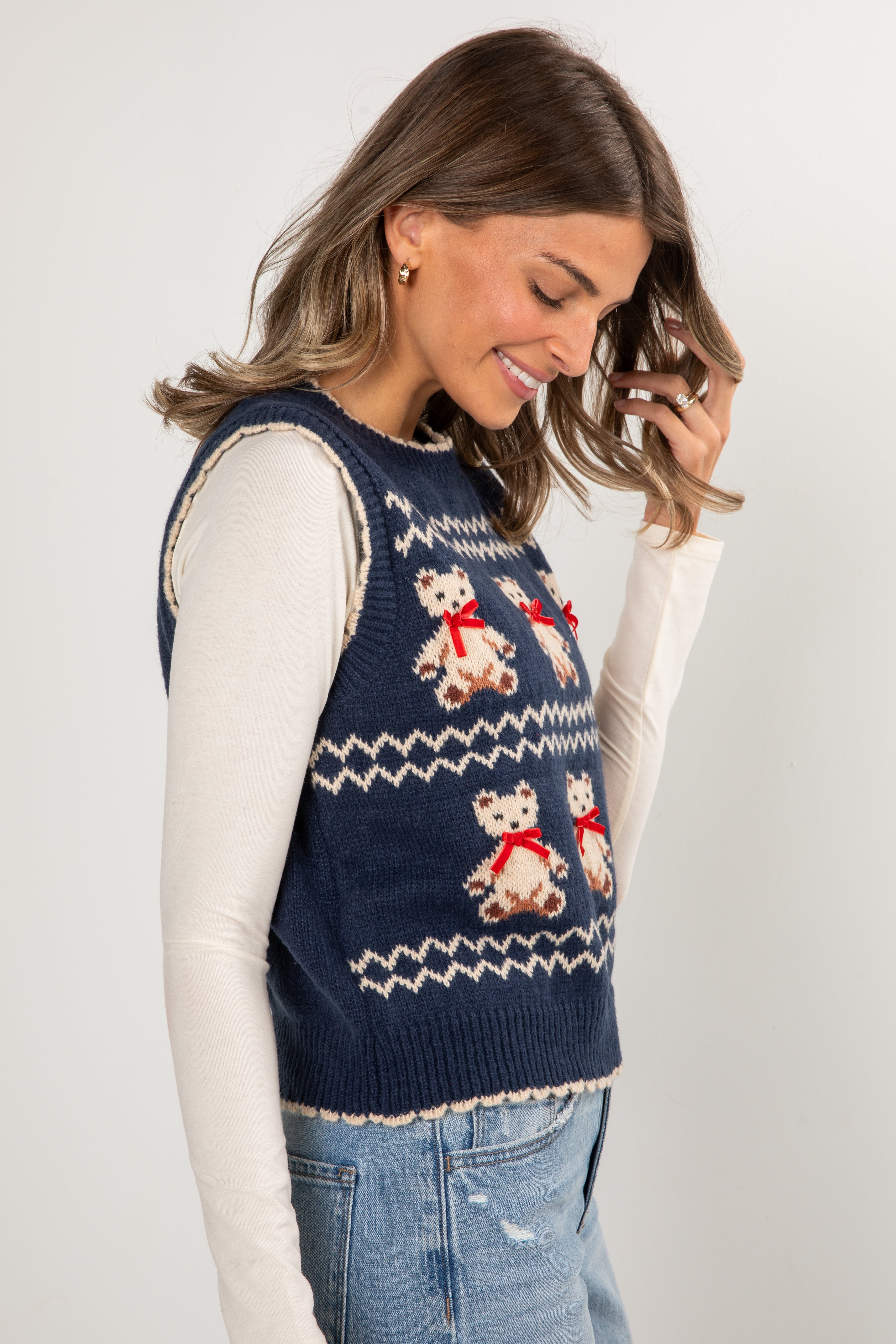Woman wearing a navy blue knitted vest with teddy bear pattern on a white background