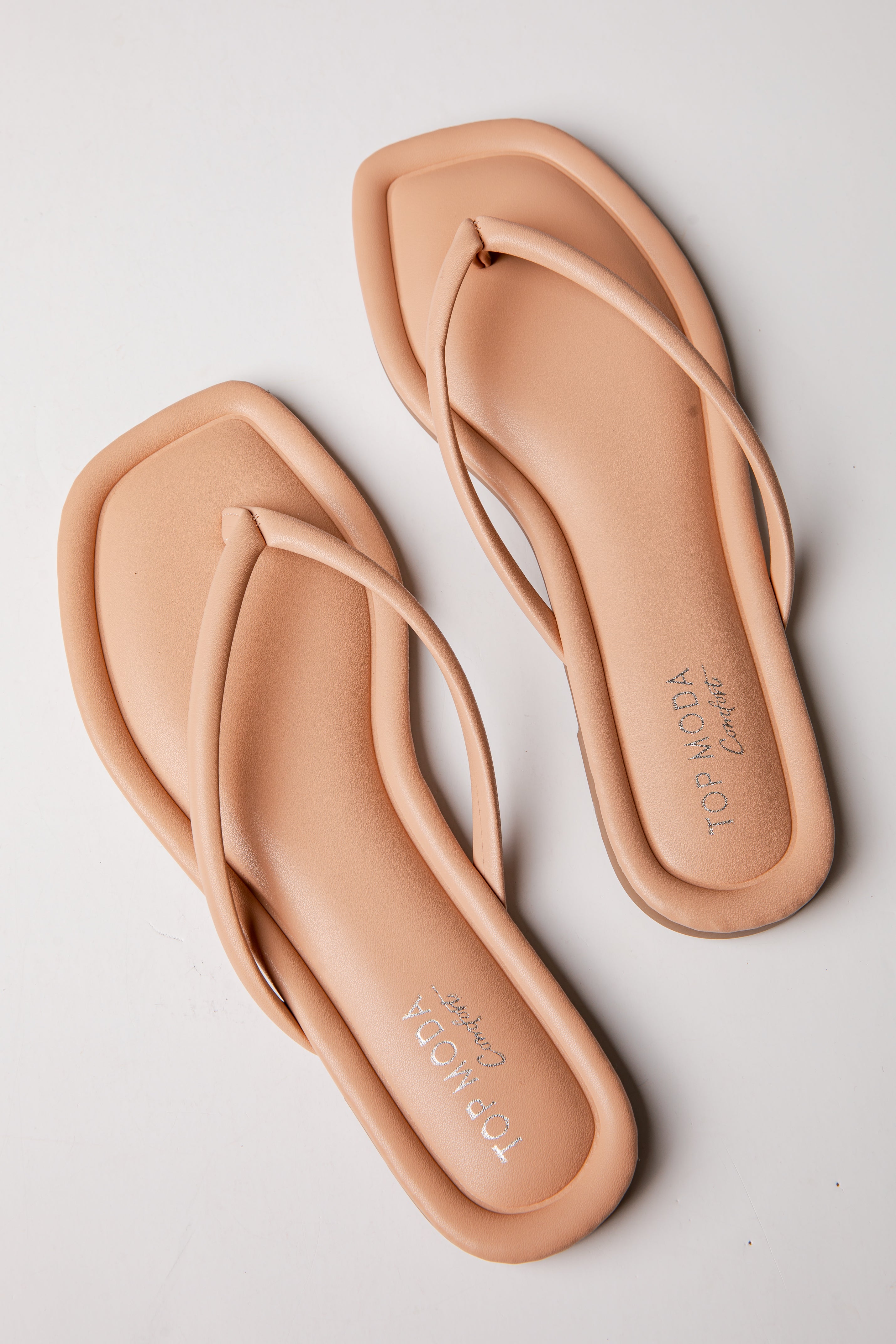 Pair of beige flip-flops on a light gray background