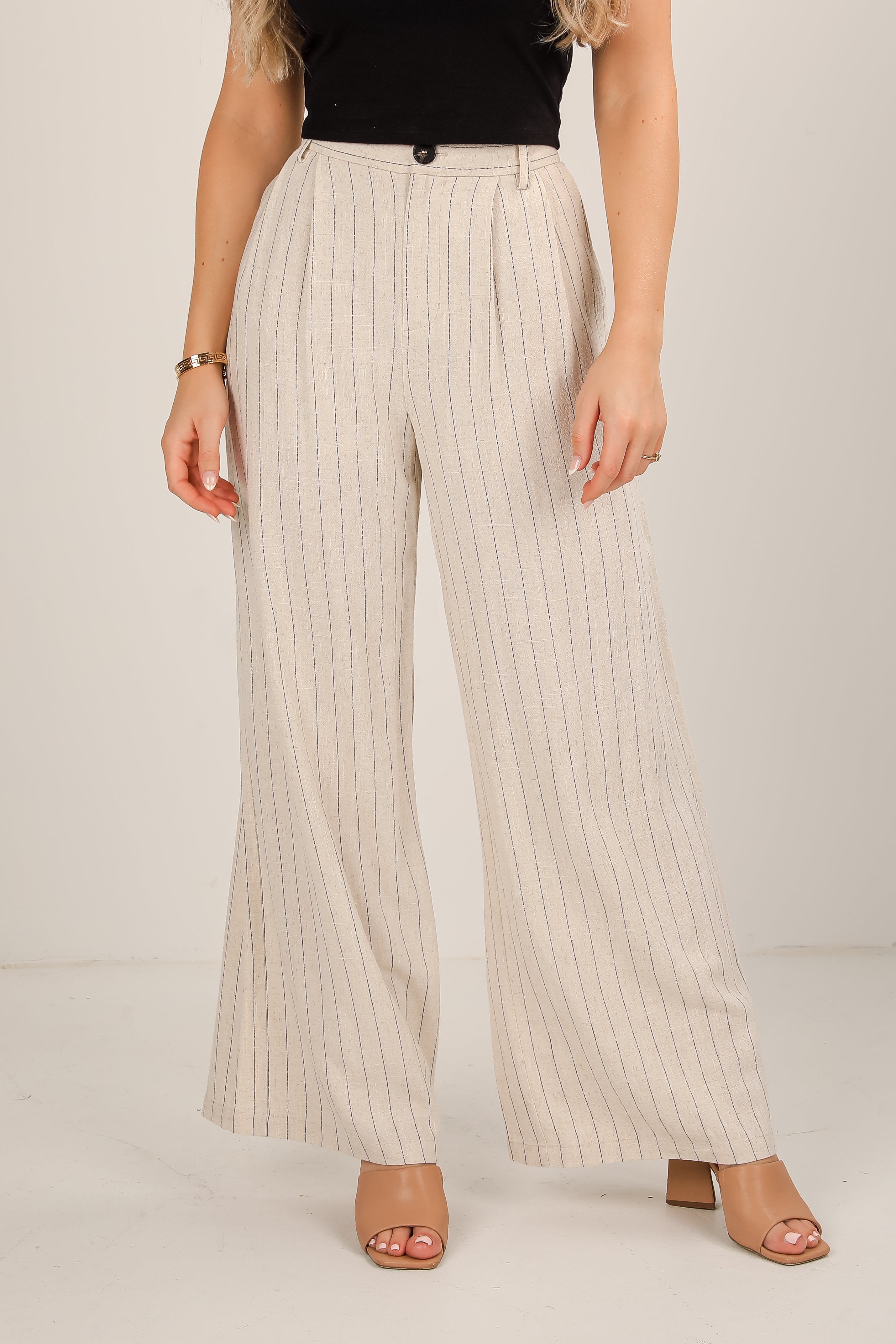 Beige pinstripe pants worn by a person on a plain background