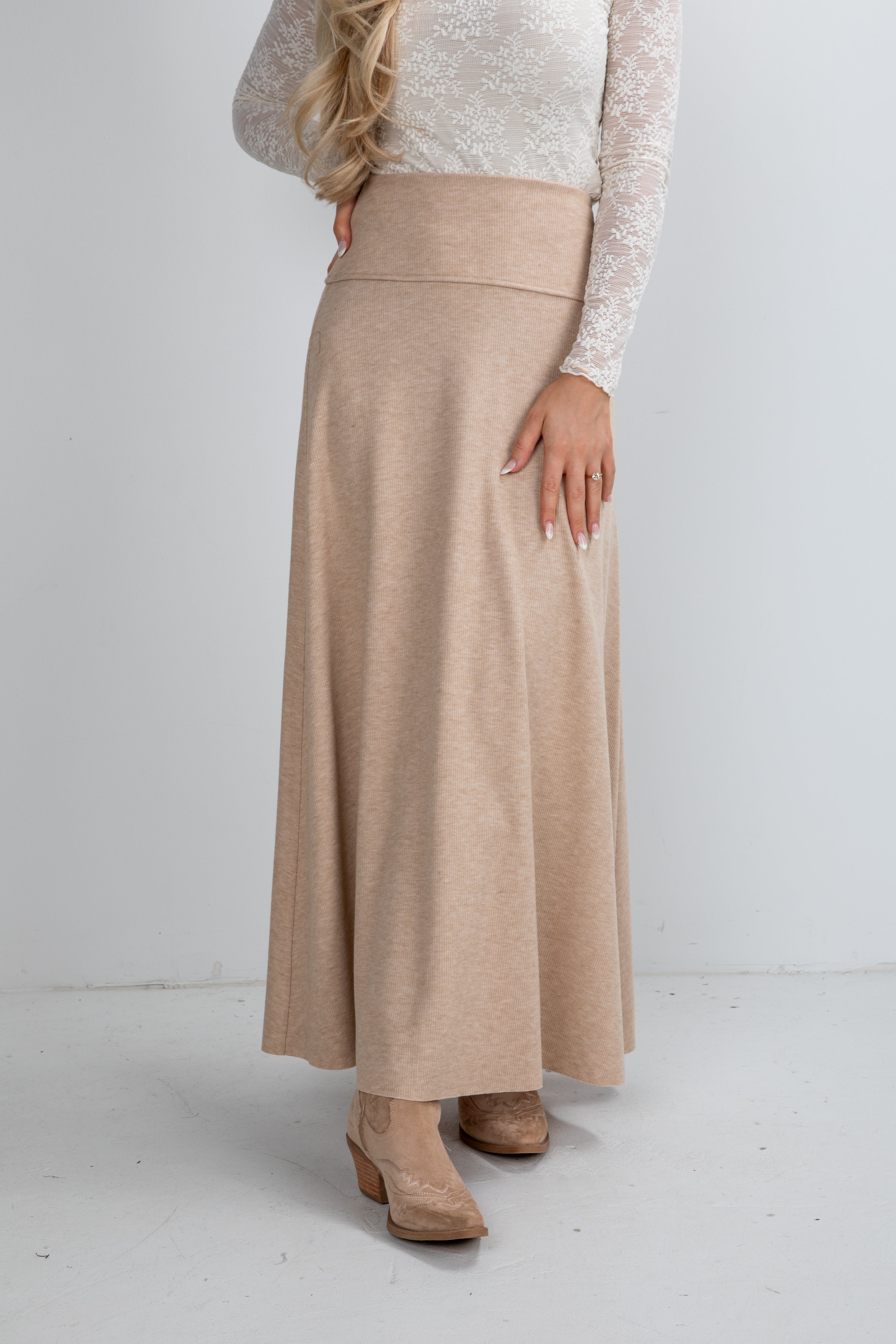 Person wearing a beige skirt and white top on a plain background