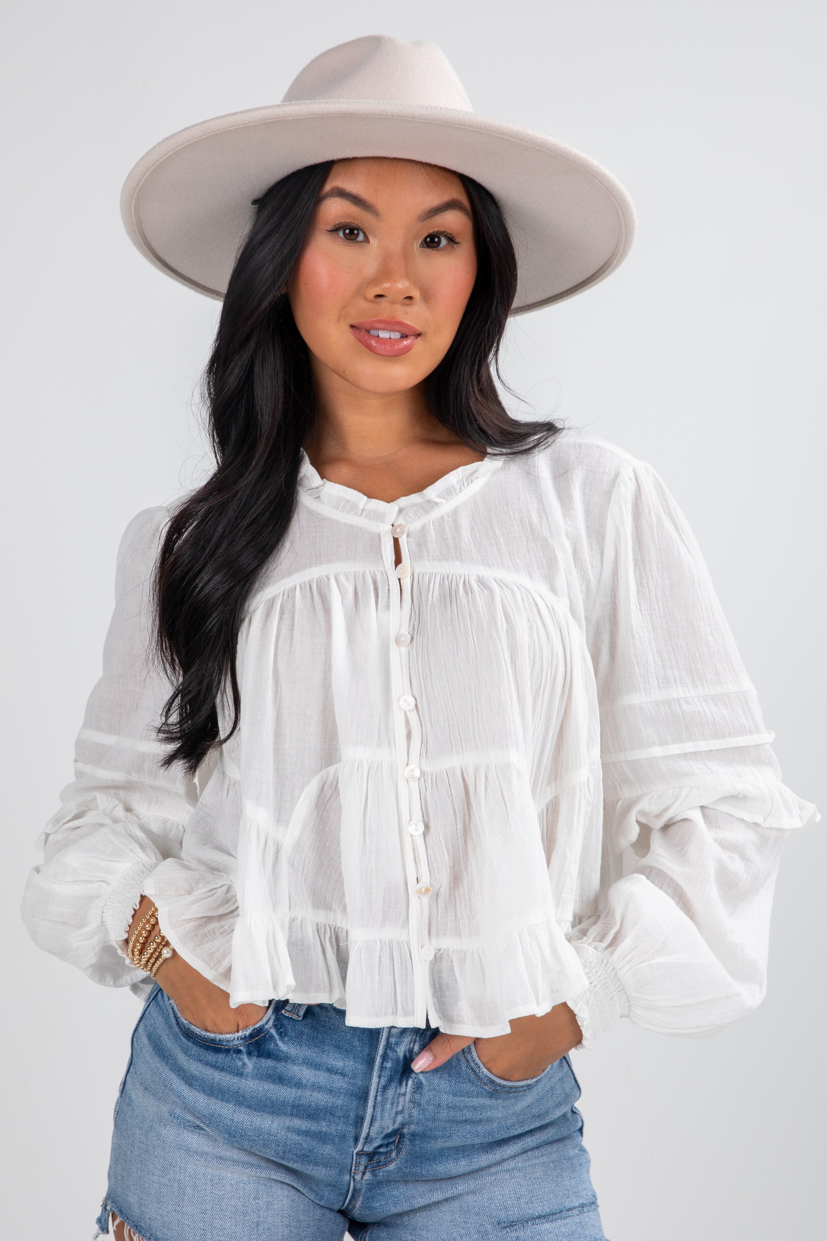 Woman wearing a white blouse and beige hat on a plain background