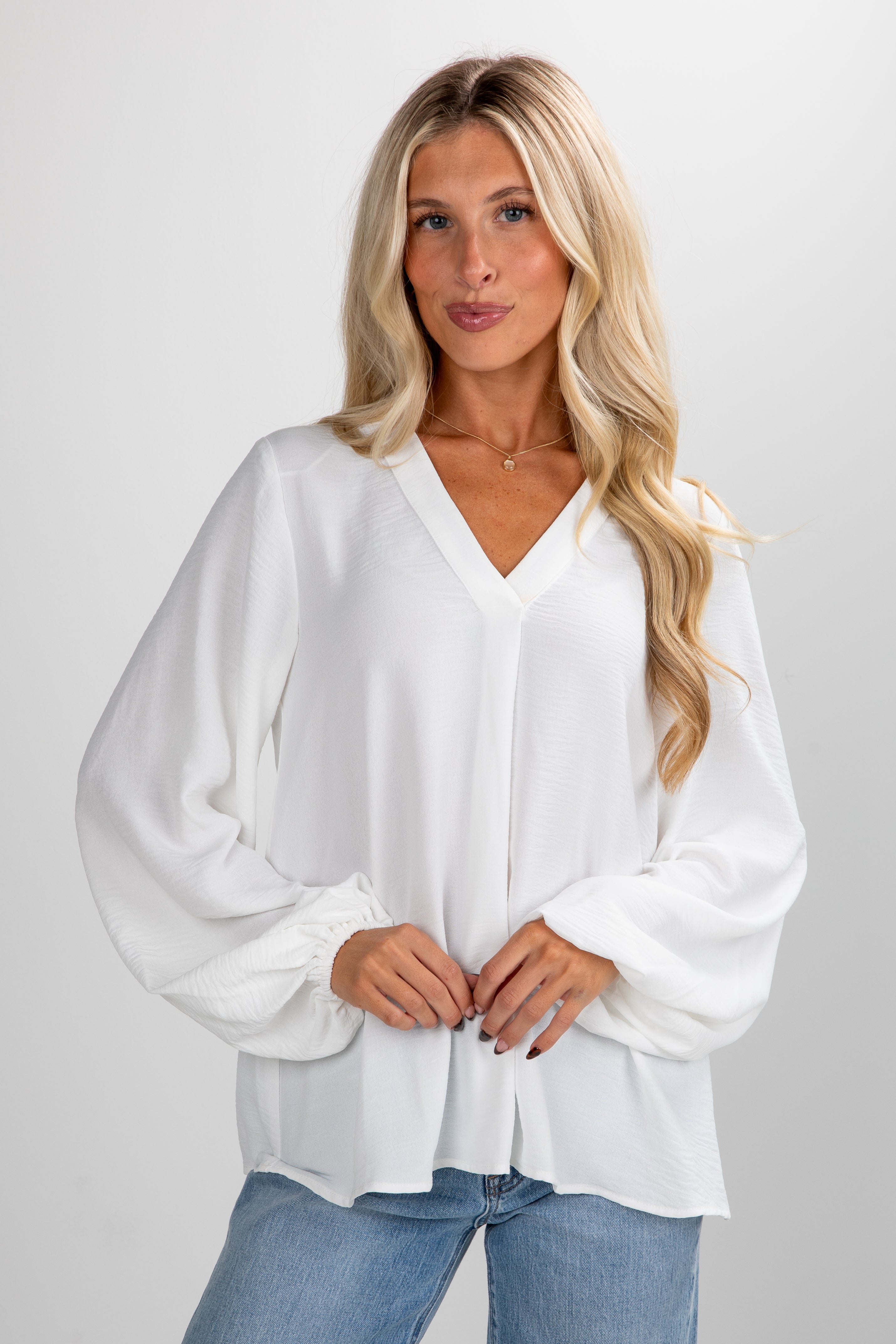 Woman wearing a white blouse and blue jeans on a plain background