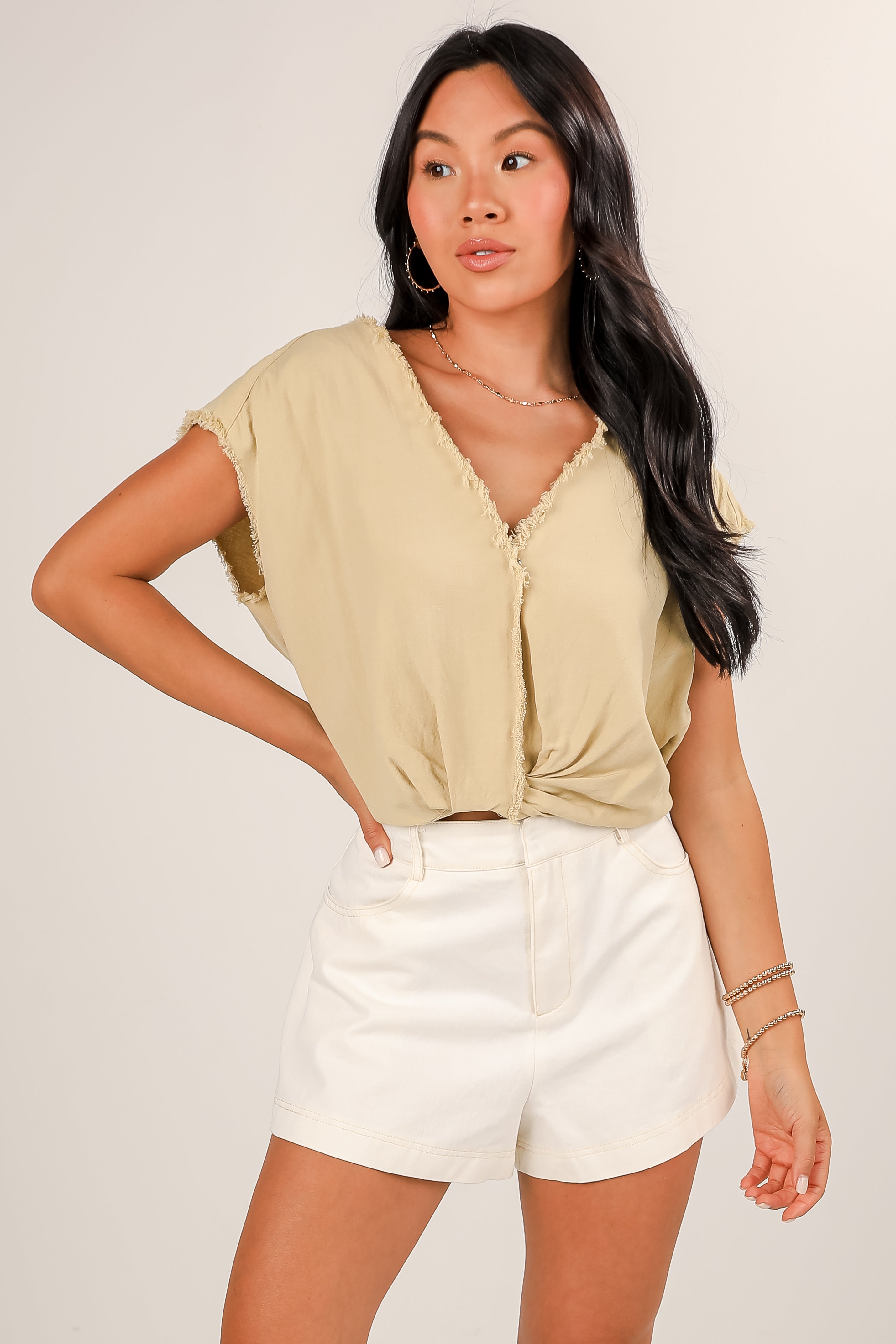 Woman wearing a light green top and white shorts against a plain background