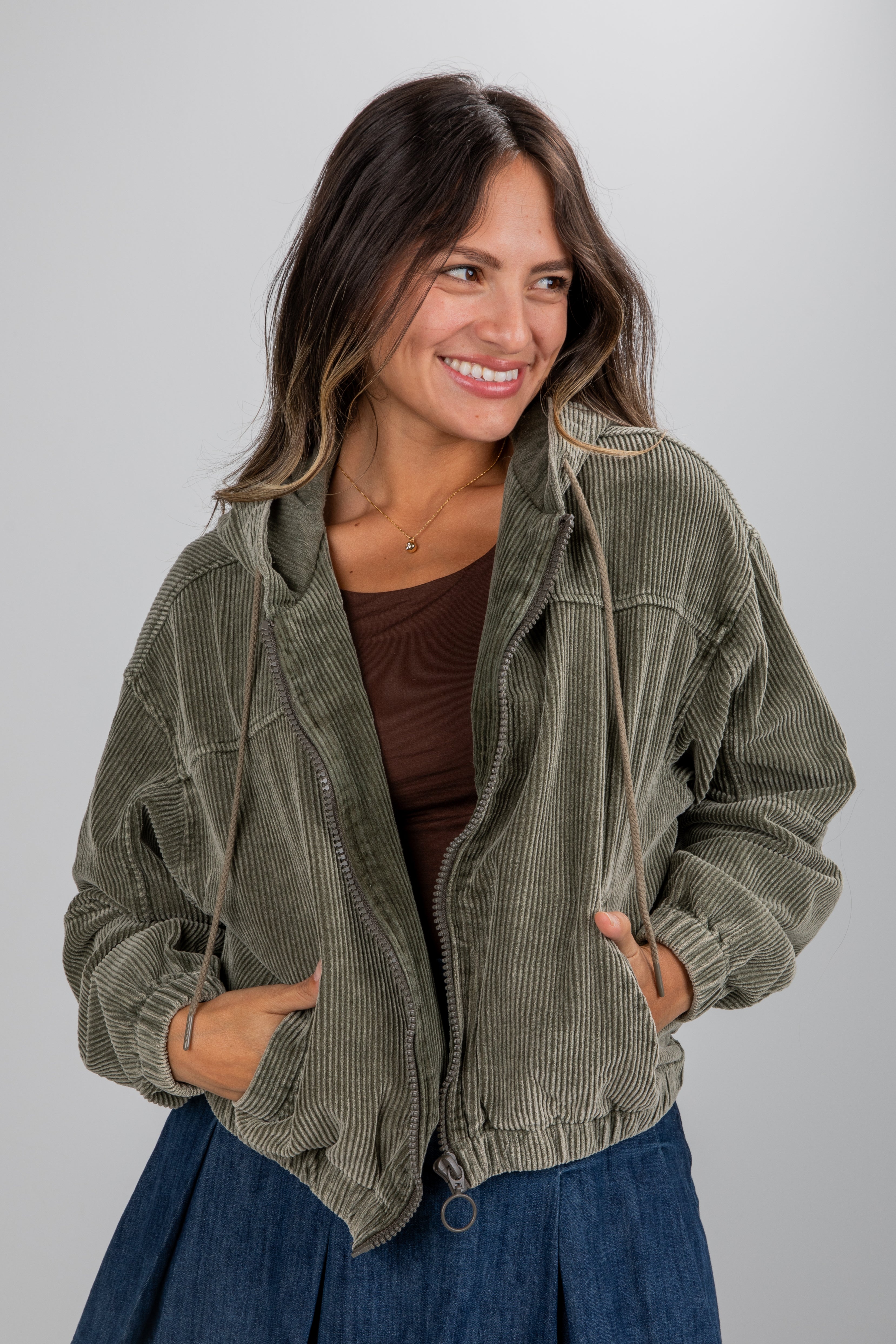 Woman wearing a green corduroy jacket on a gray background