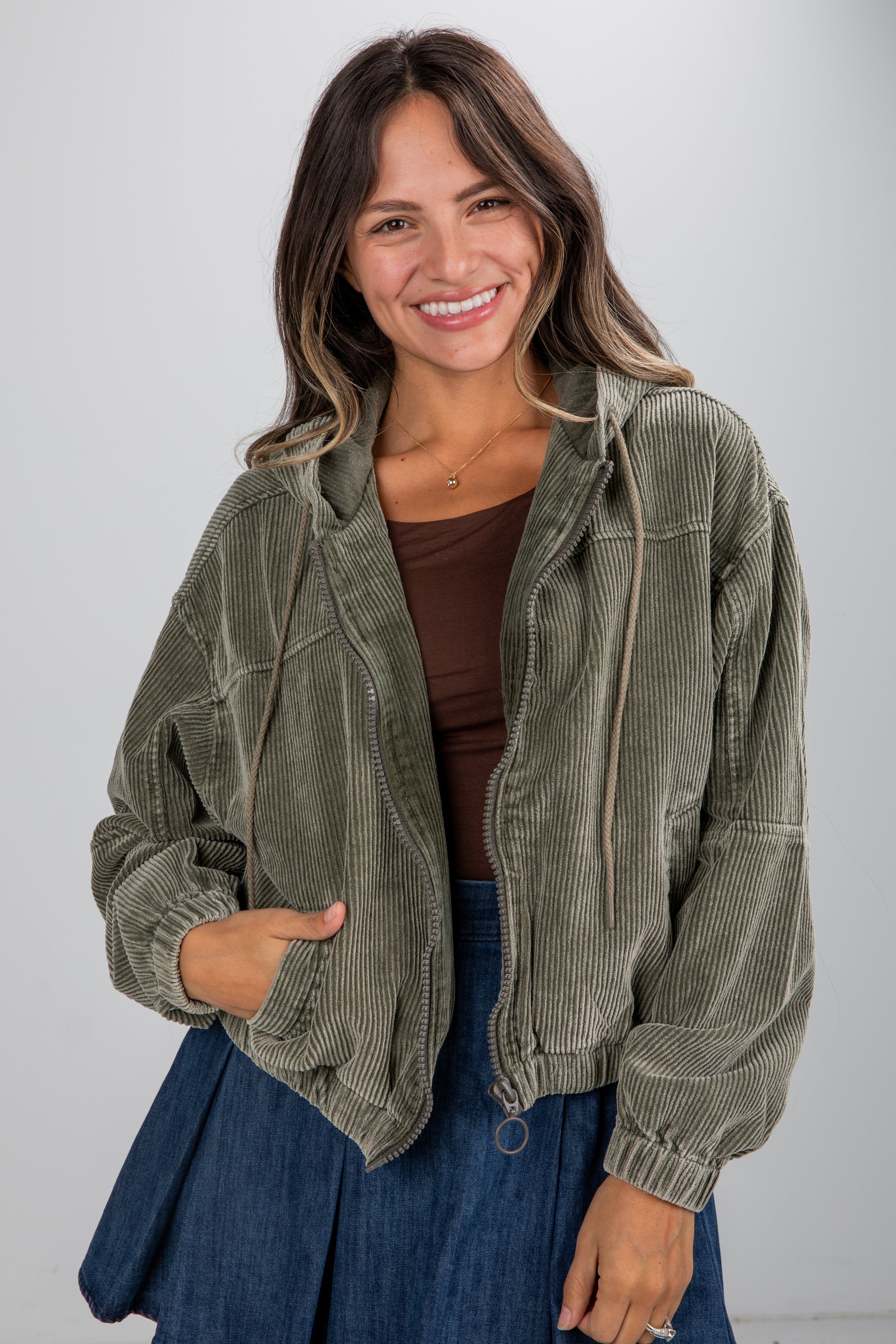 Woman wearing a green corduroy jacket against a plain background