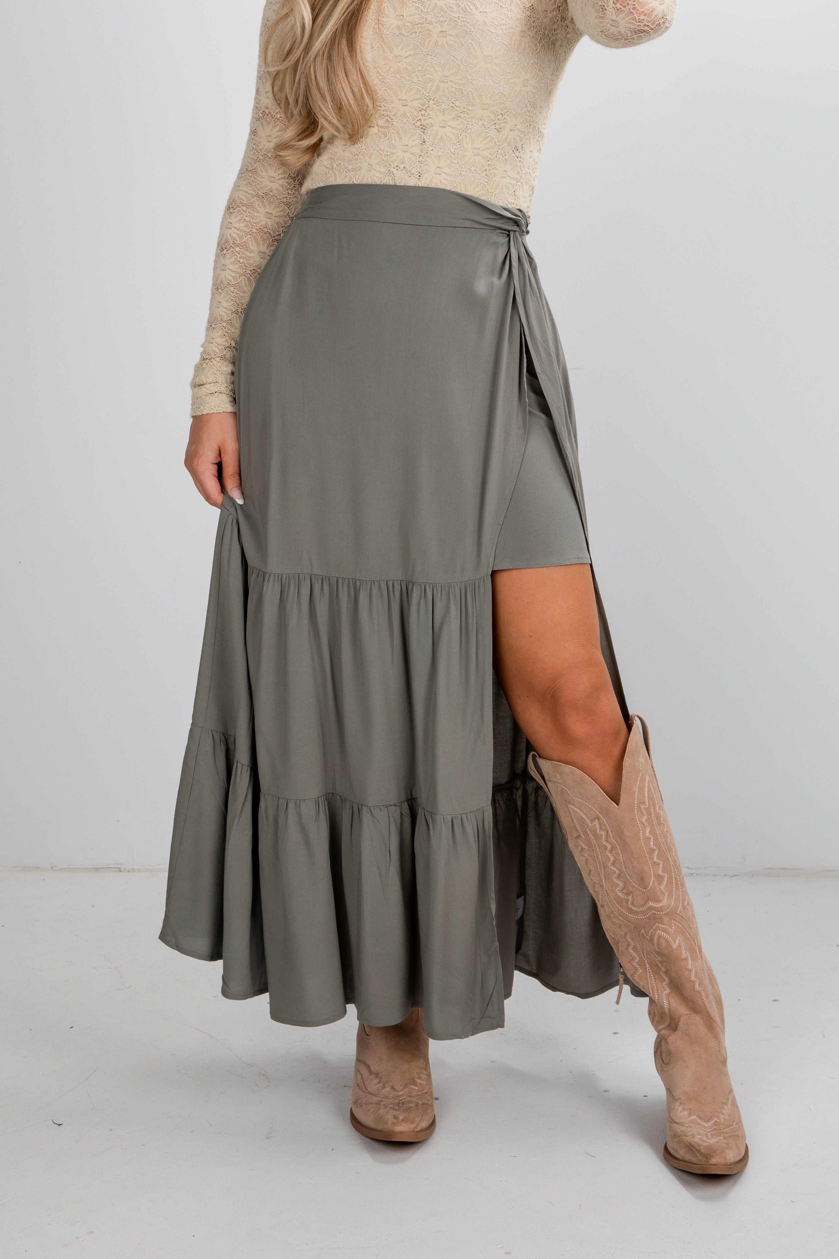 Person wearing a long green skirt with a white background