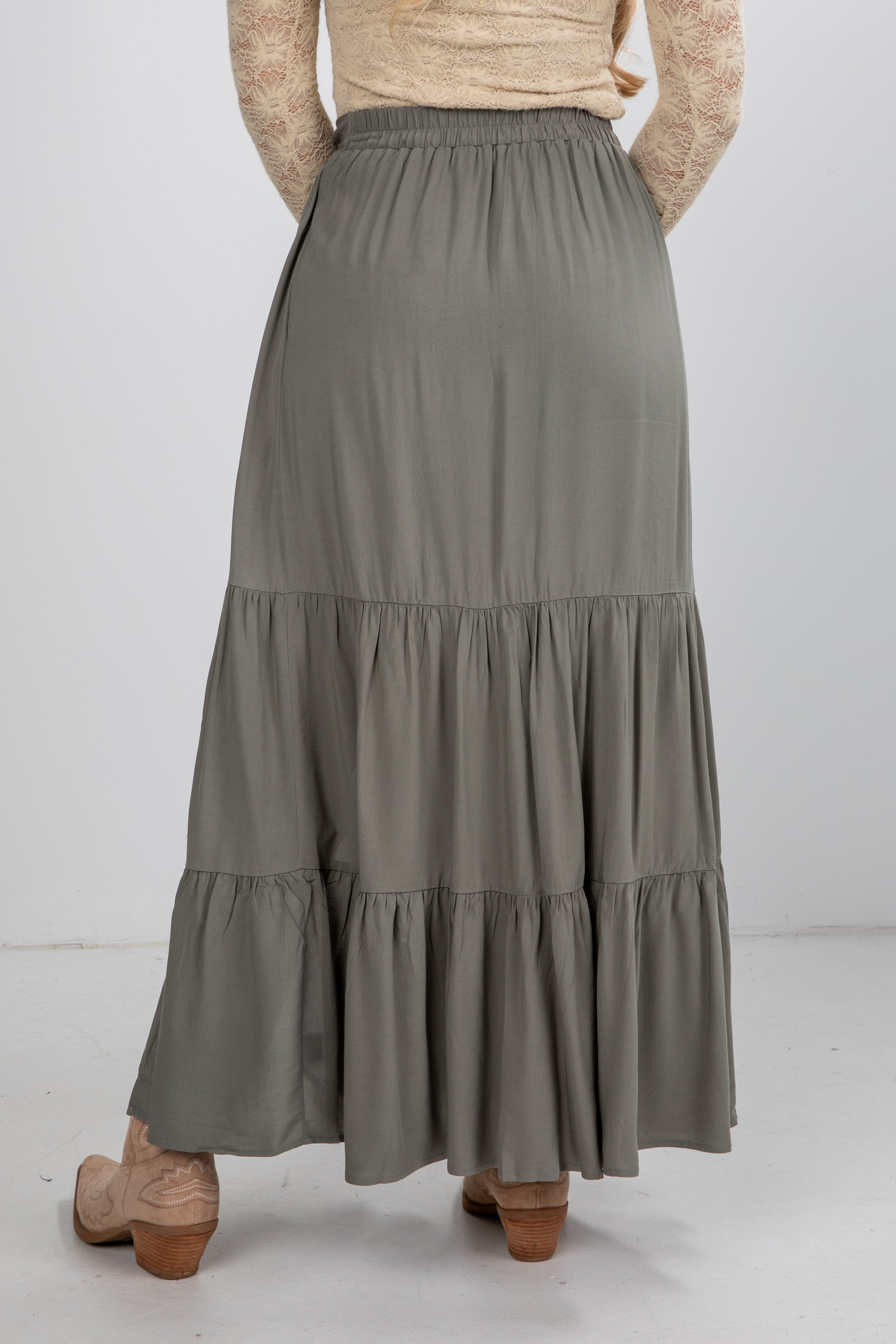 Person wearing a long, tiered gray skirt on a white background