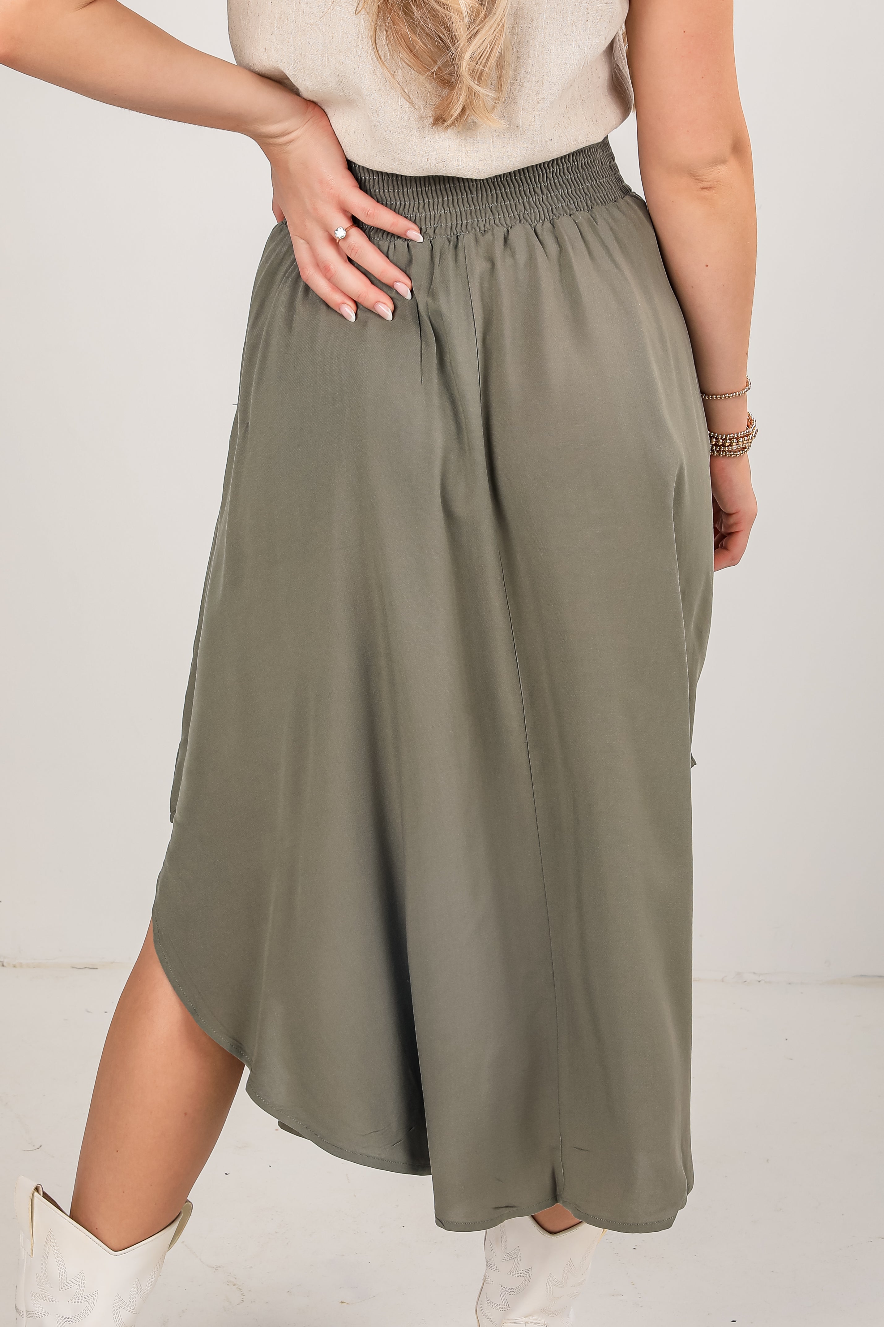 Person wearing a long olive green skirt on a plain background