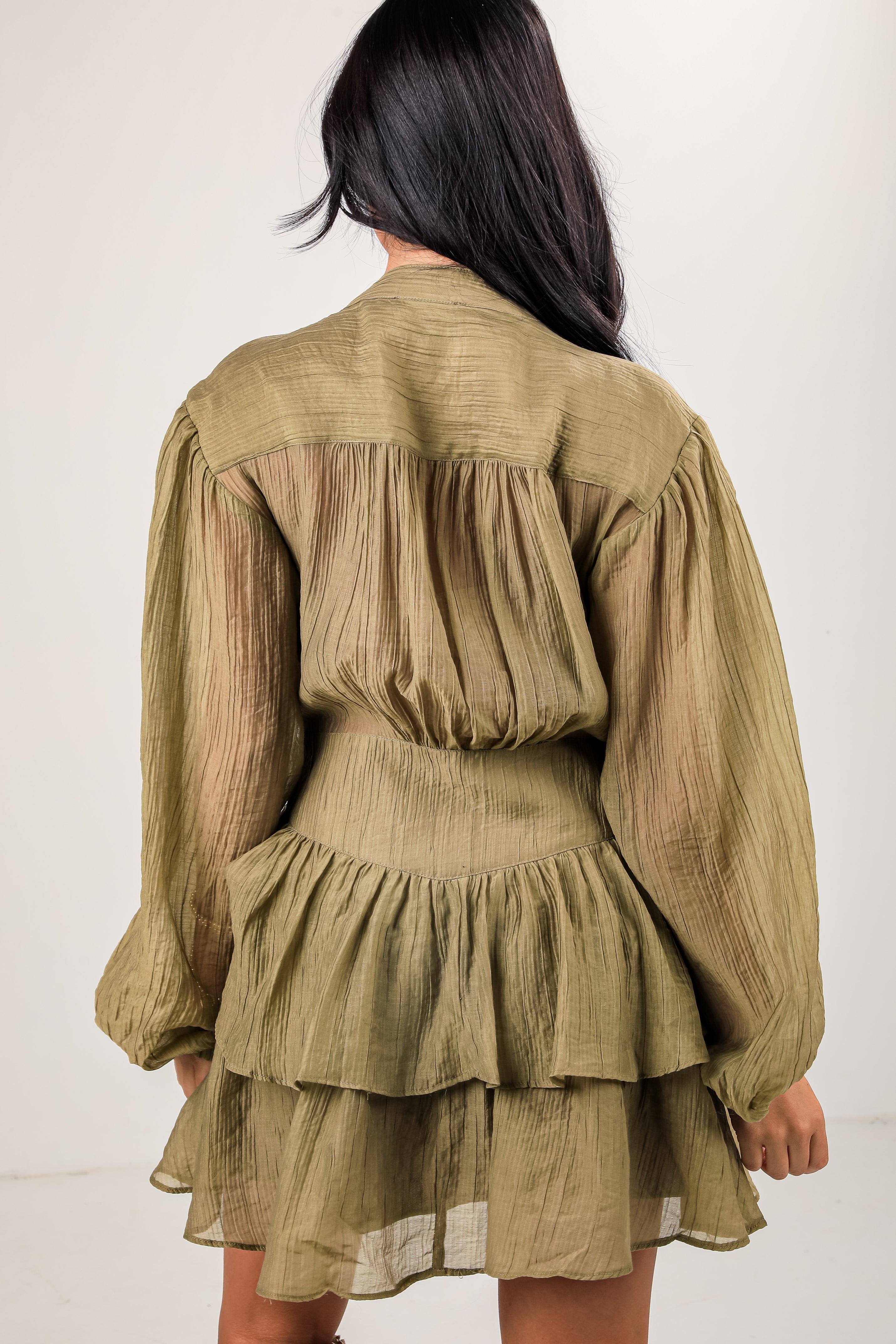 Woman wearing a green pleated dress against a white background