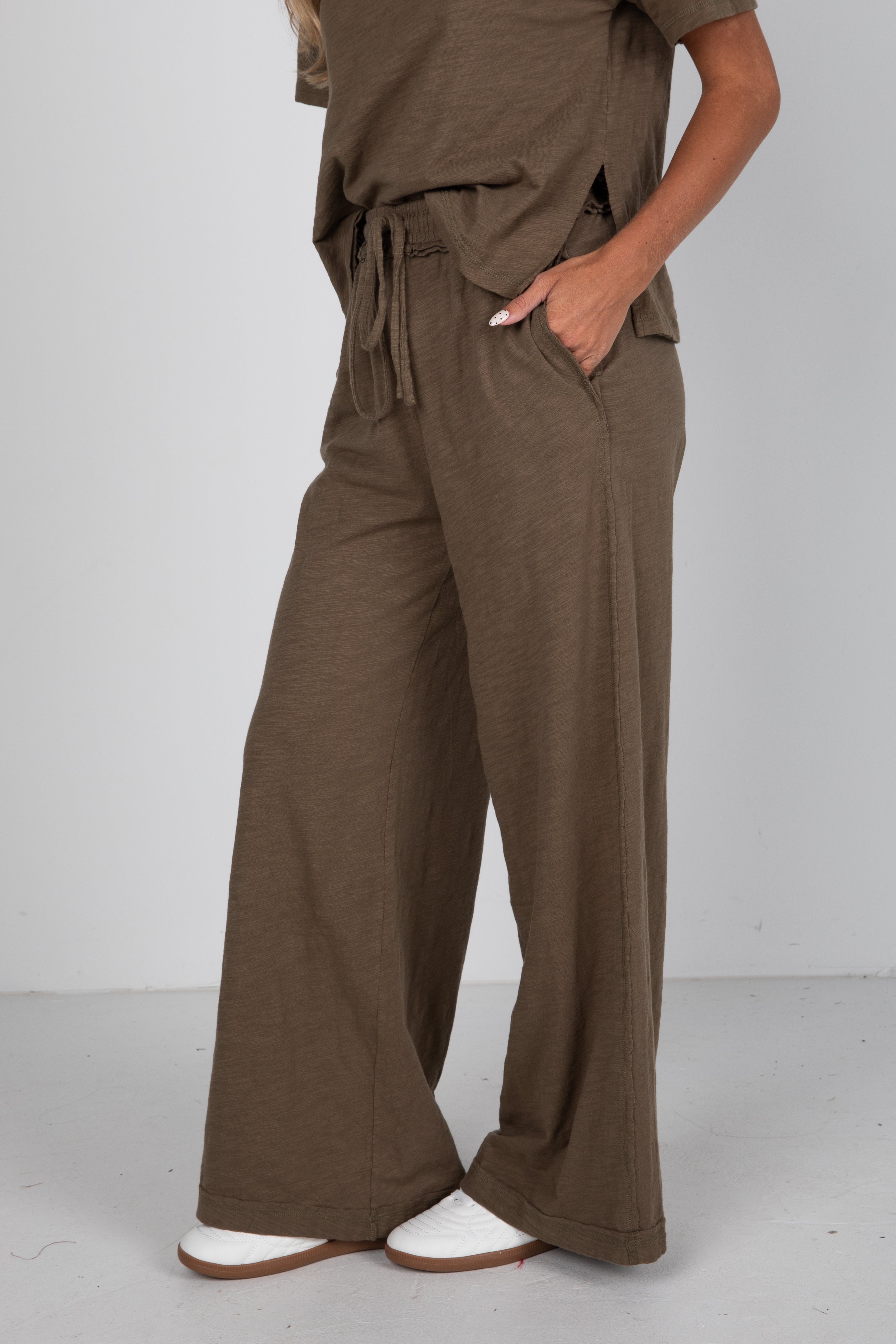Person wearing brown pants and a matching top on a white background