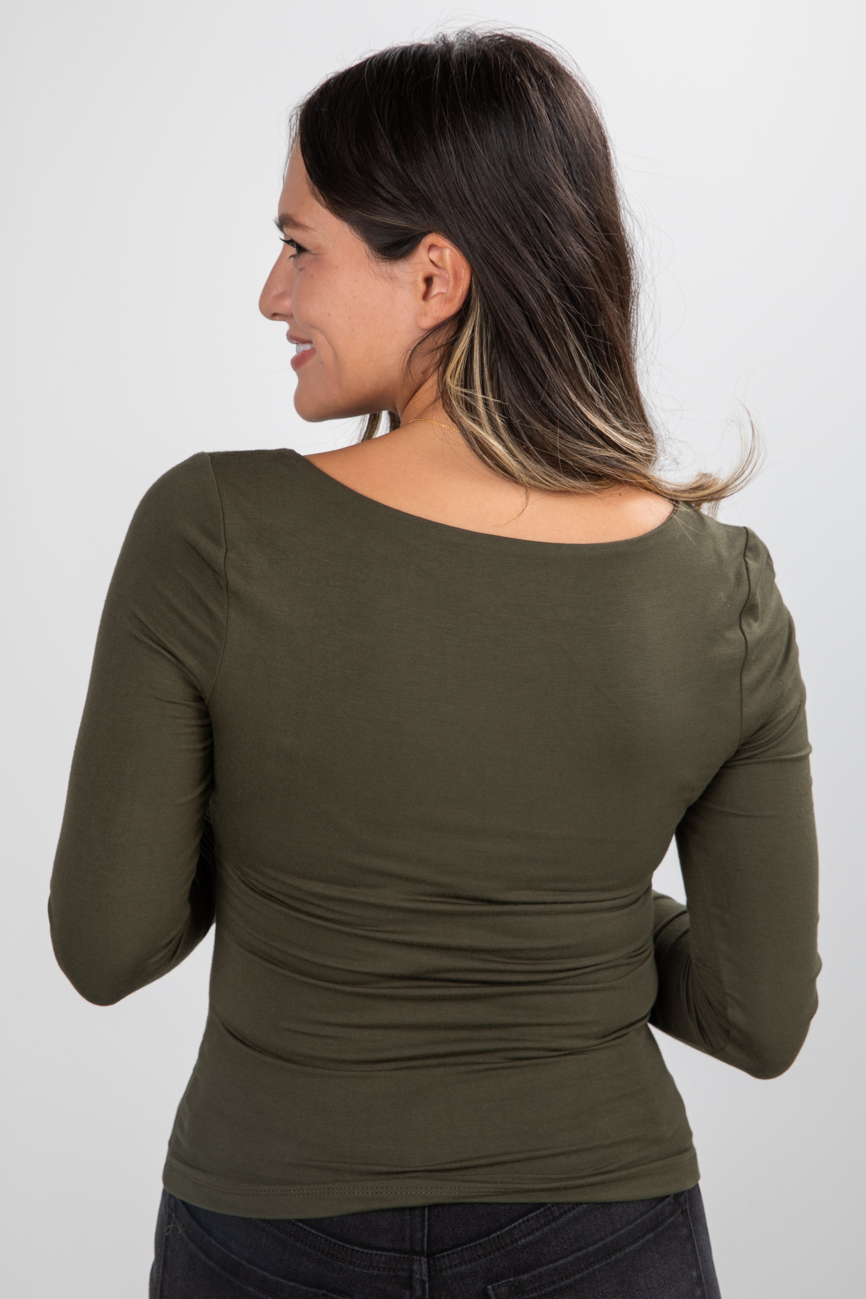 Woman wearing an olive green long-sleeve top against a white background