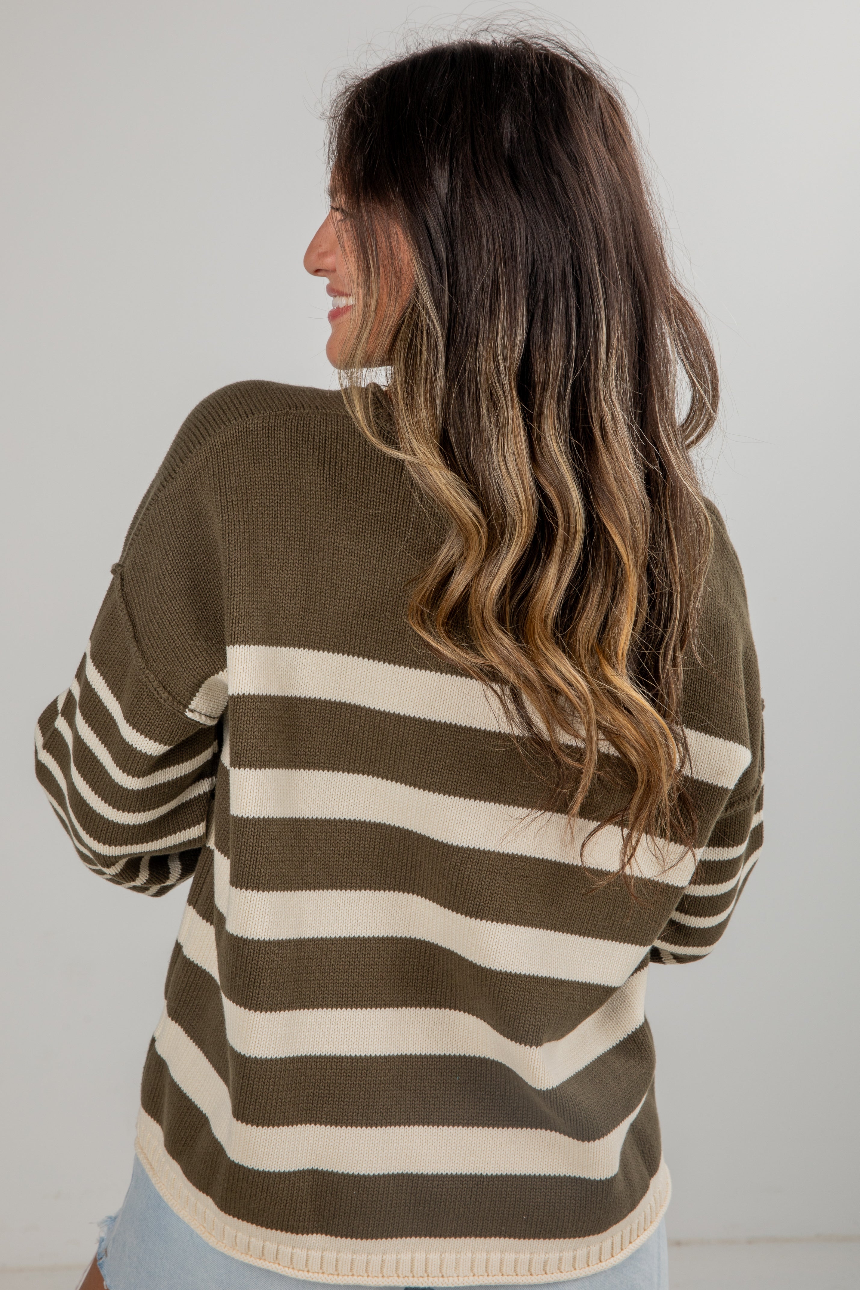 Woman wearing a brown and beige striped sweater against a plain background