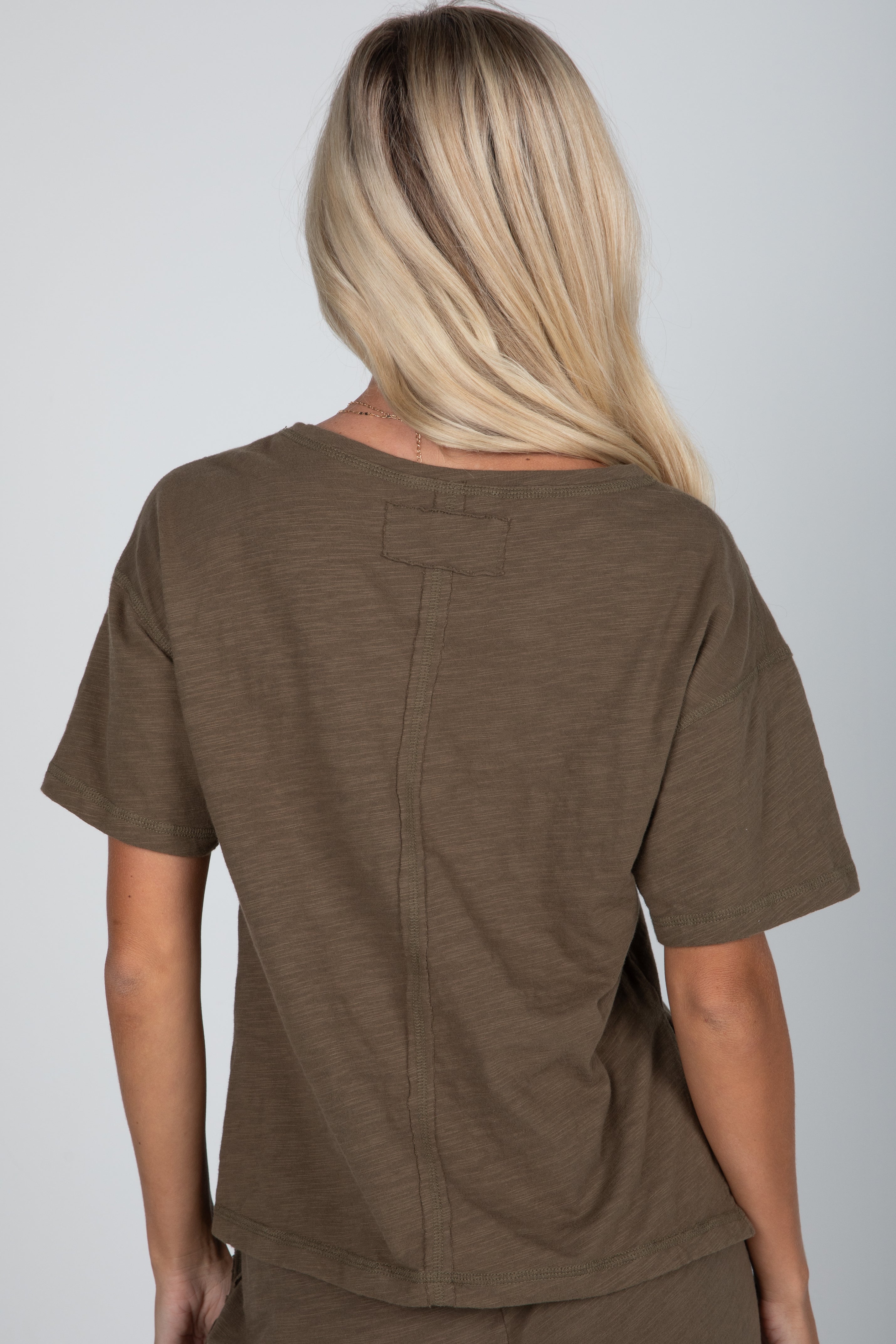 Person wearing a brown scrub top on a plain background