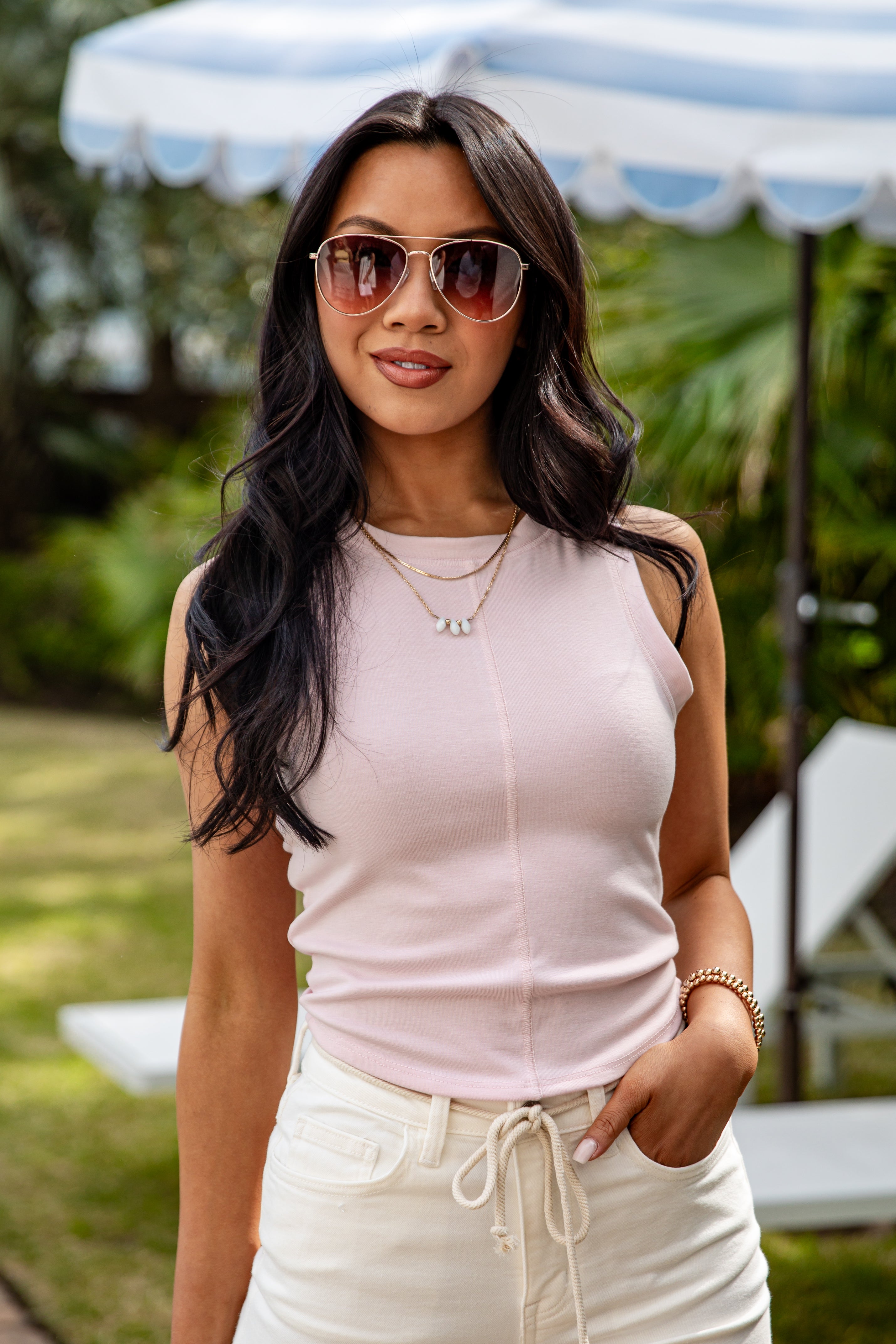 Woman wearing sunglasses and a light pink top outdoors