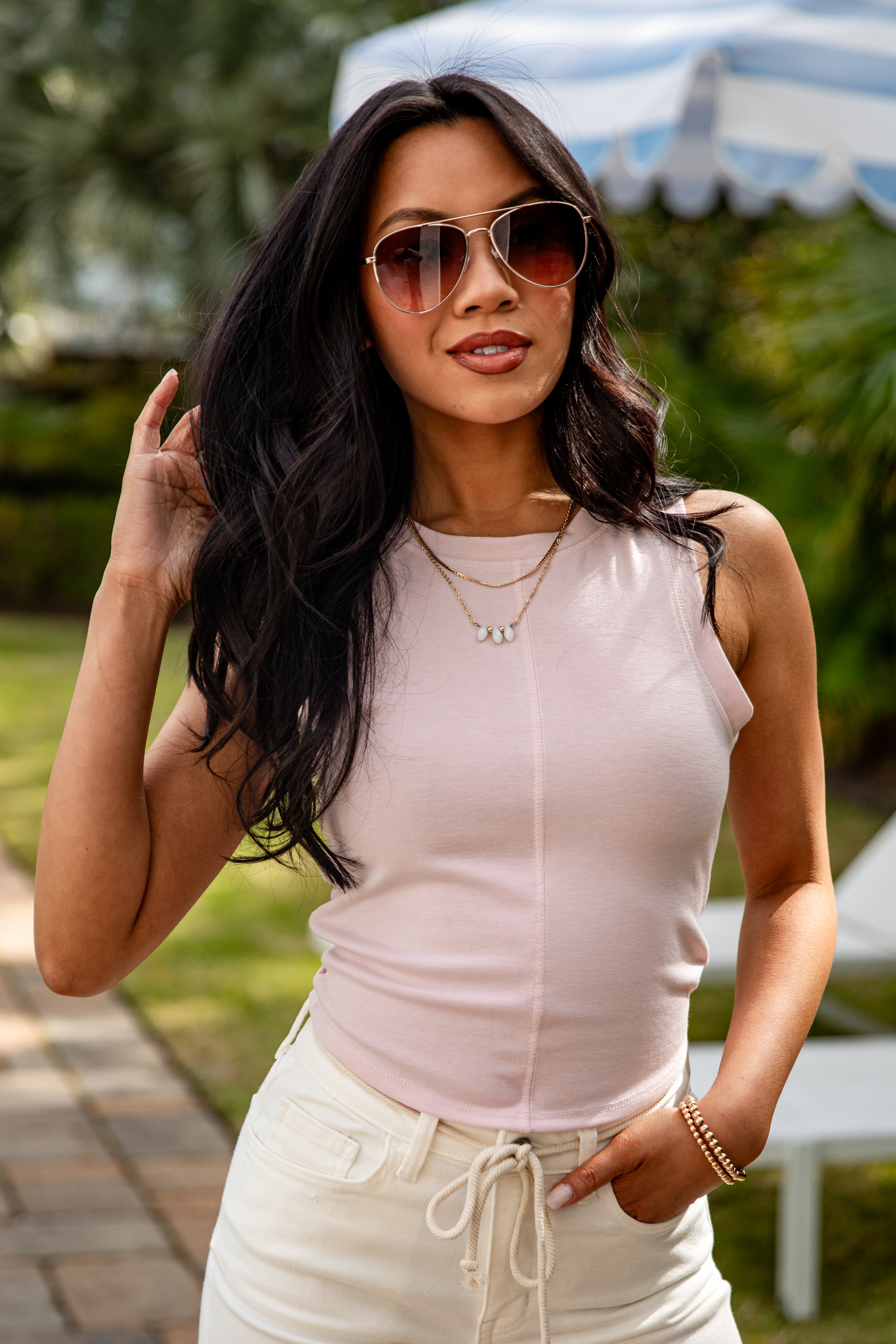 Woman wearing sunglasses and a light pink top outdoors
