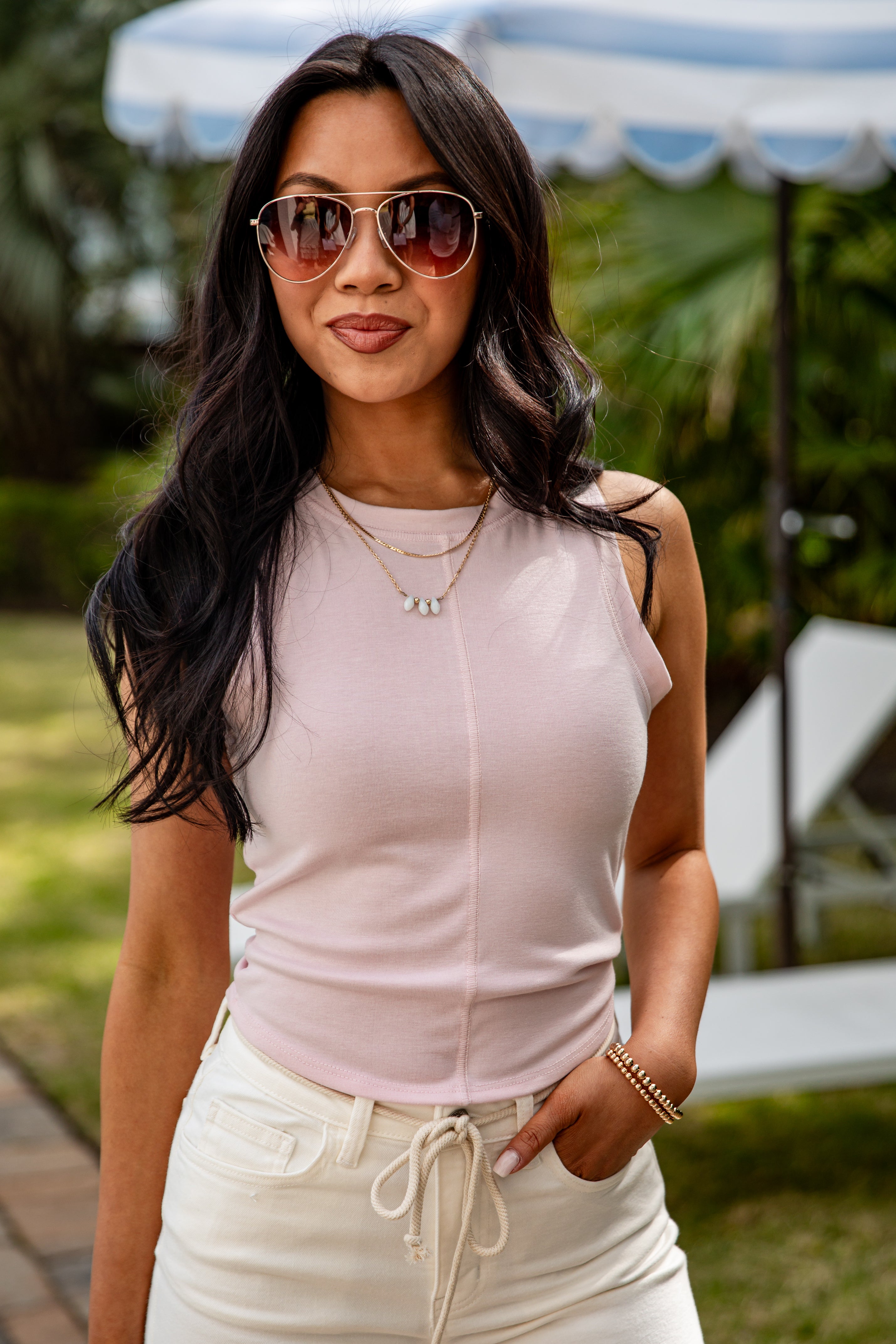 Woman wearing a light pink top and white pants outdoors