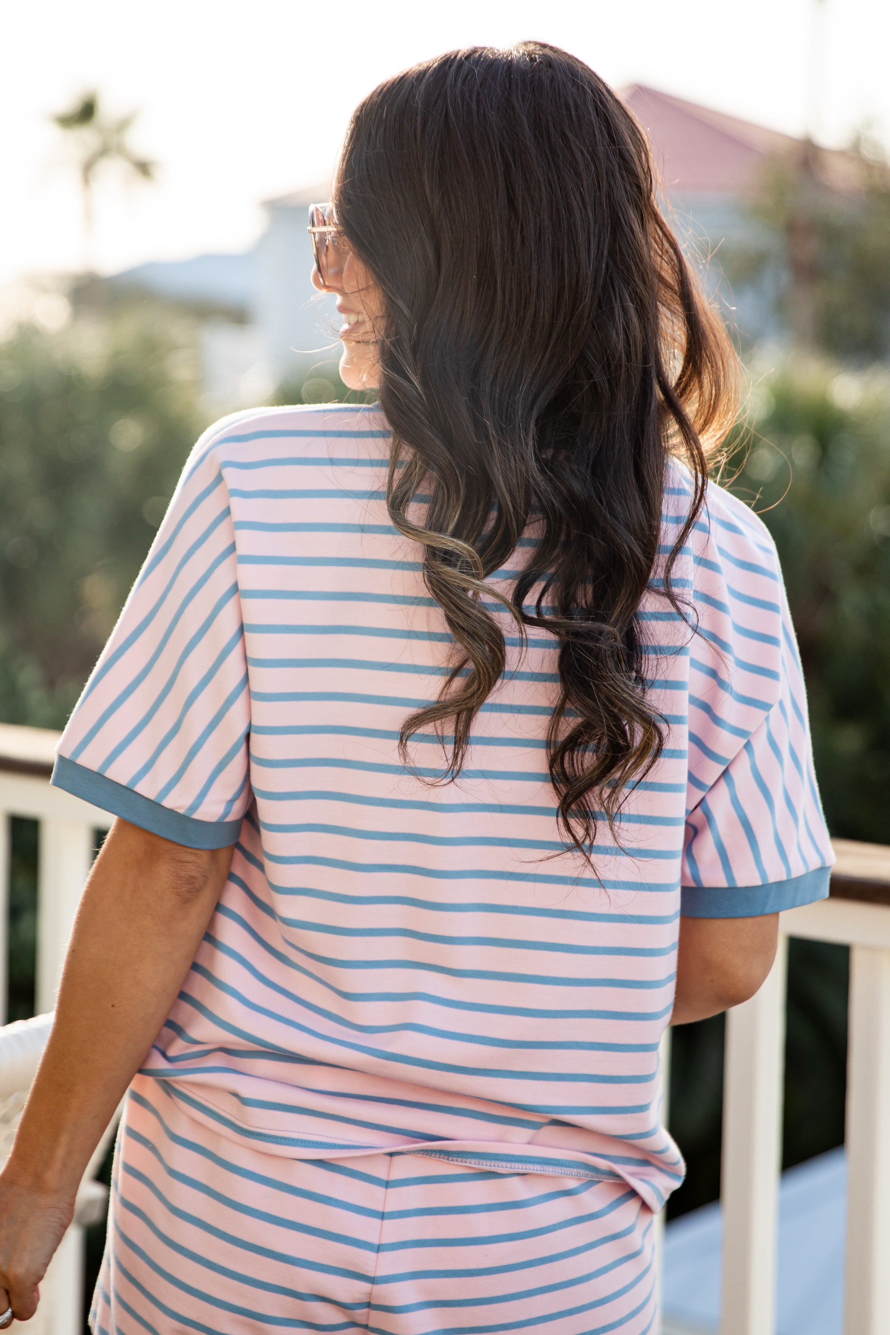 Woman wearing a striped pajama set on a balcony with blurred background