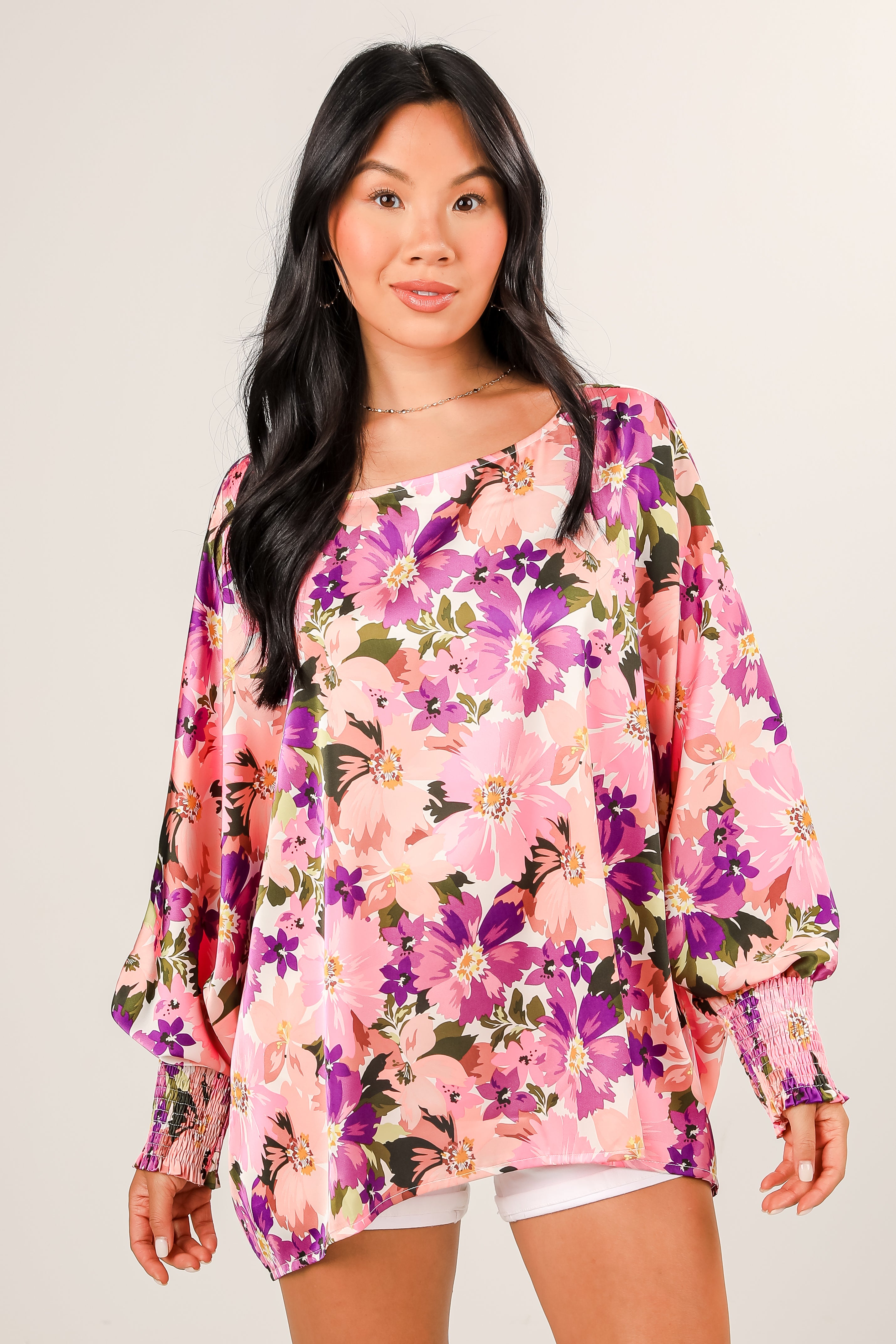 Woman wearing a colorful floral blouse against a plain background