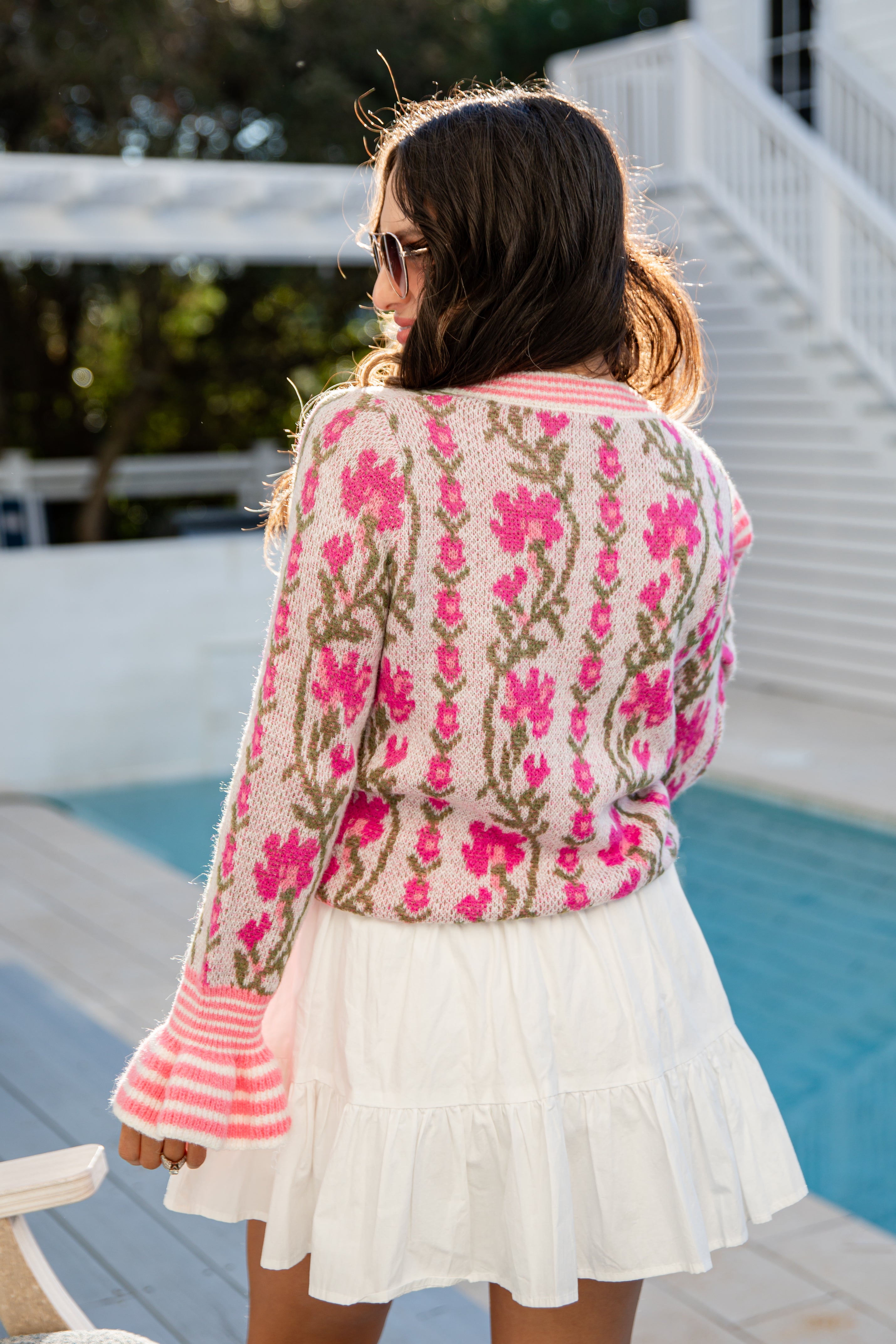 Woman wearing a floral embroidered jacket by a poolside