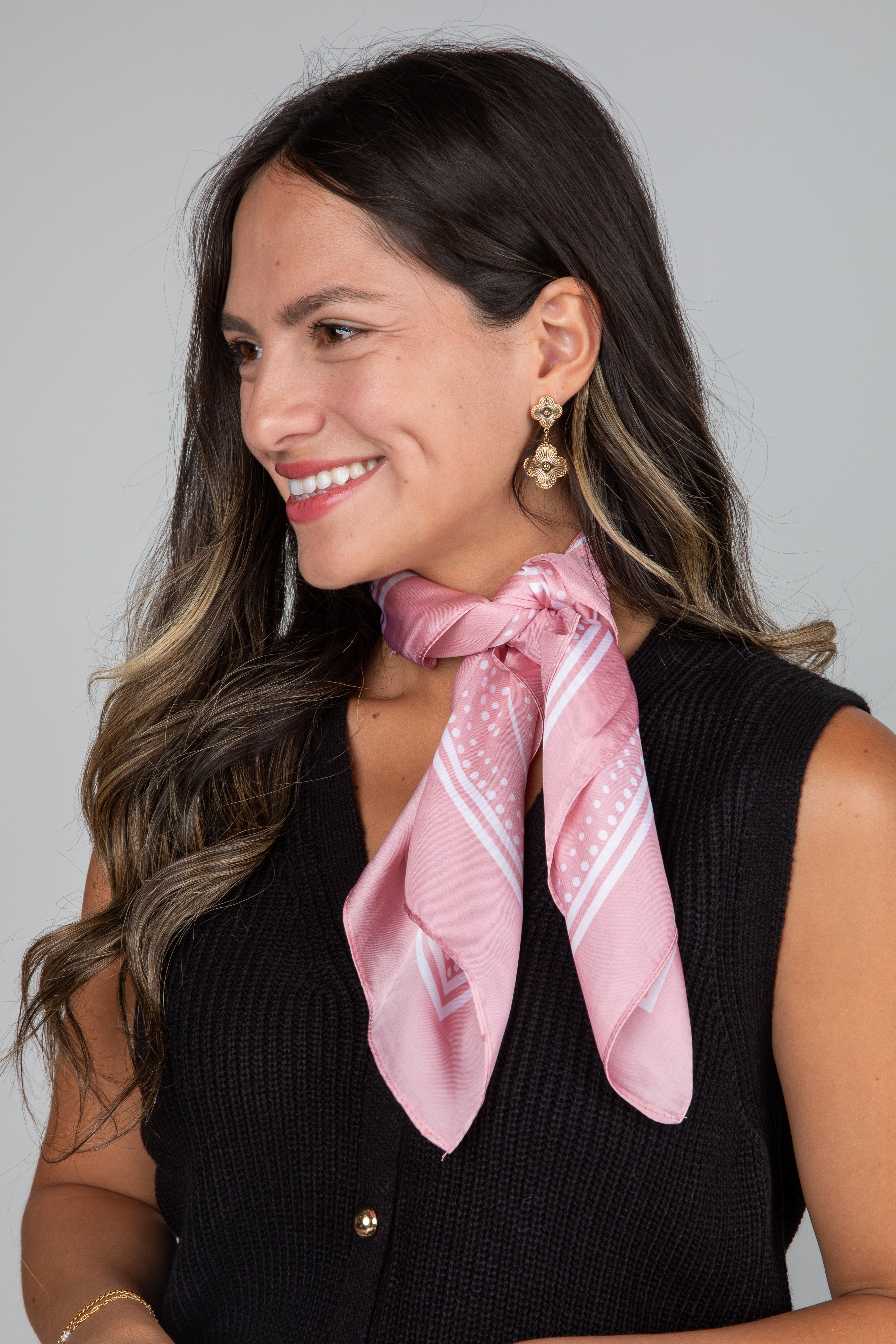 Woman wearing a pink scarf with a subtle pattern on a plain background
